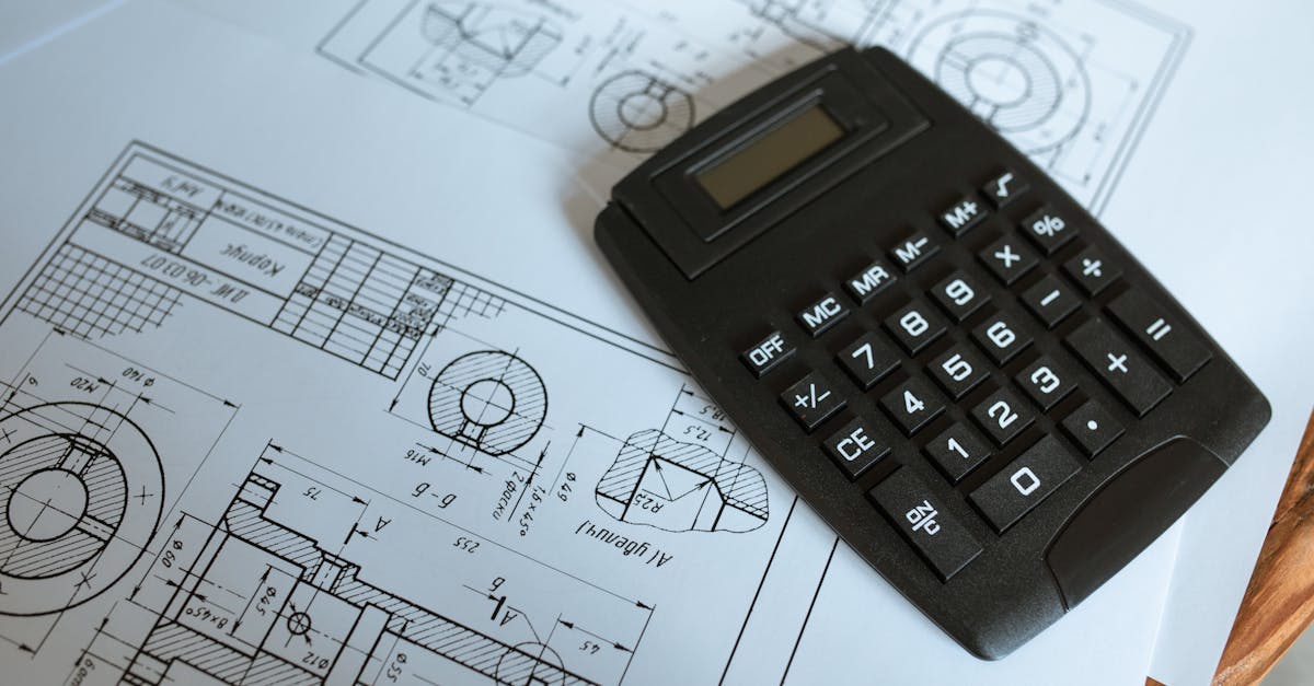 Close-up of a calculator resting on technical engineering blueprints, showcasing precise calculation