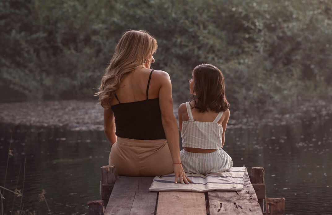 Mother and daughter sitting at the edge of the creek having a meaningful conversation