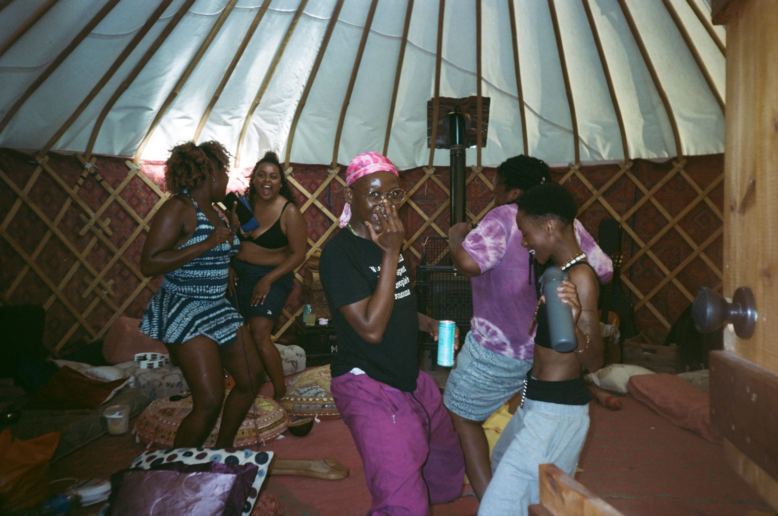 A group of people are dancing and laughing inside a yurt
