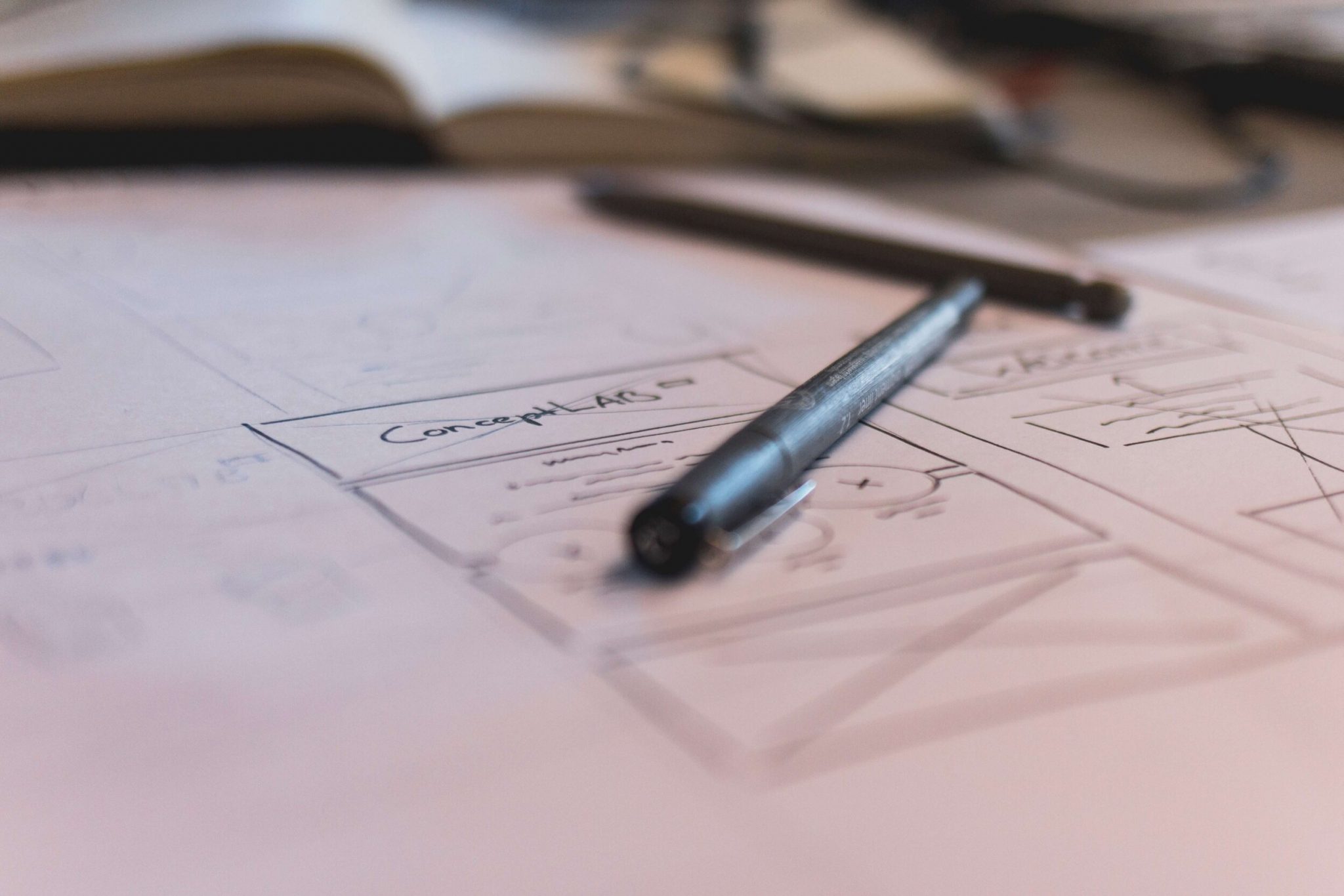A black pen resting on a sheet of sketched wireframes