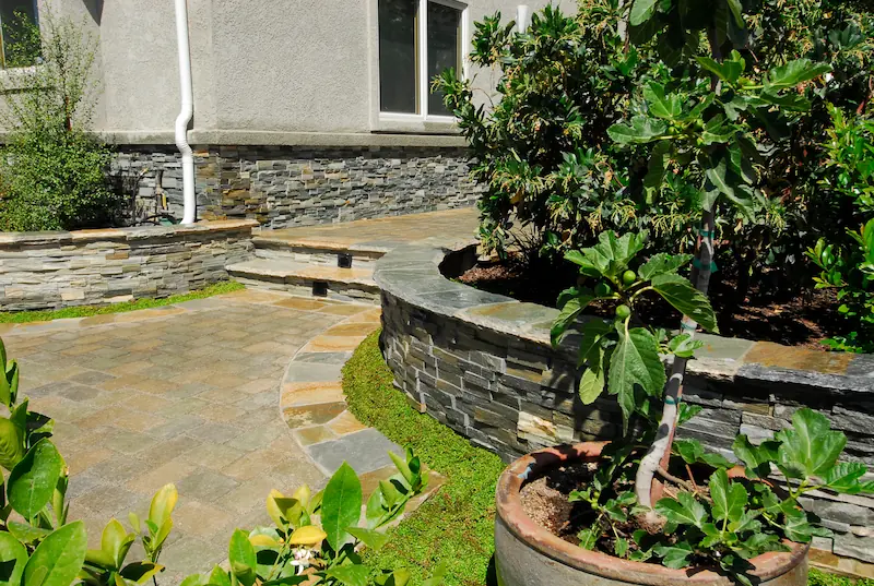 Lush garden path with stone pavers and stacked stone planters in Irvine Transitional Modern. Photo by Chris Darnall.