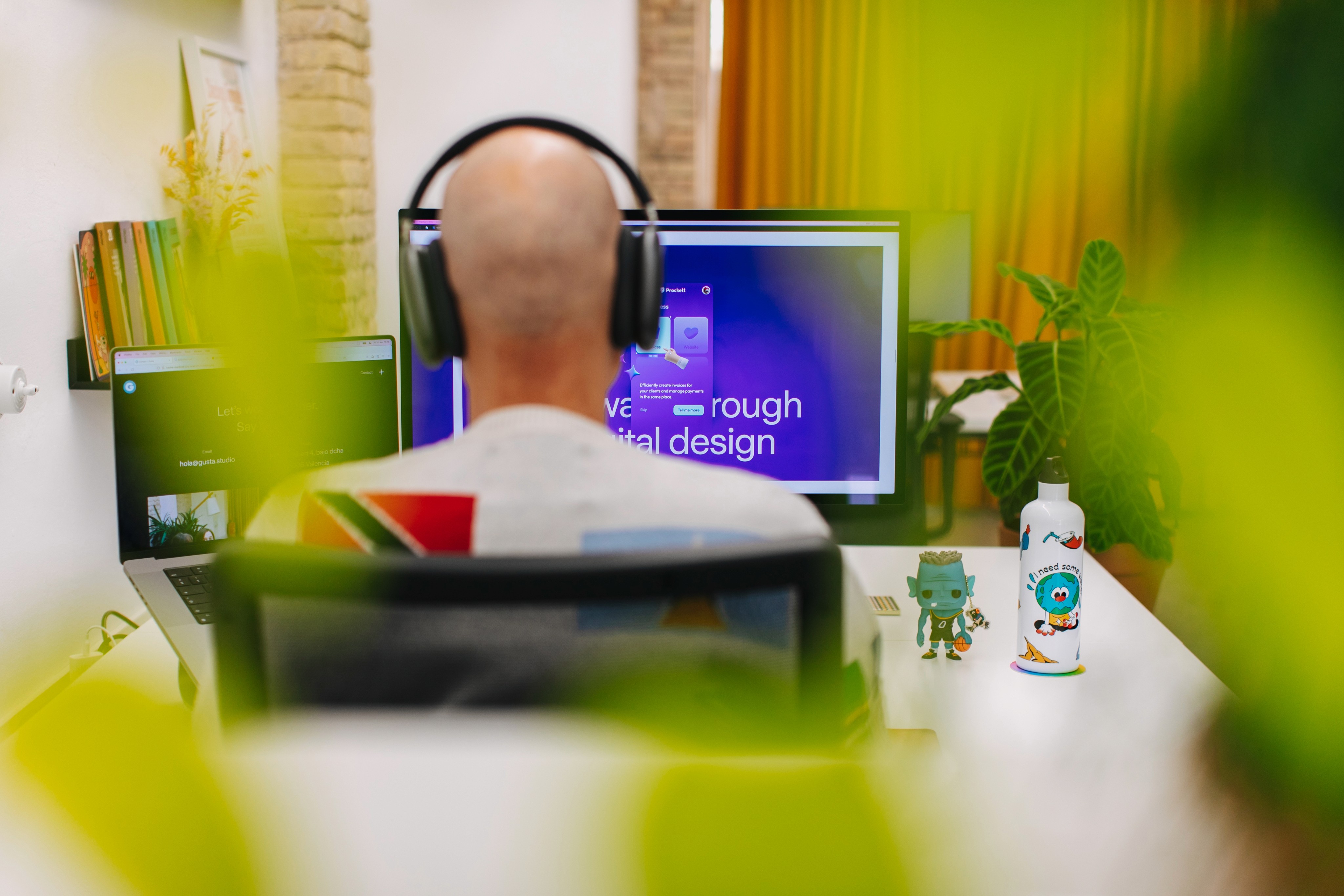 A man working on a desgin at his desk while wearing headphones.