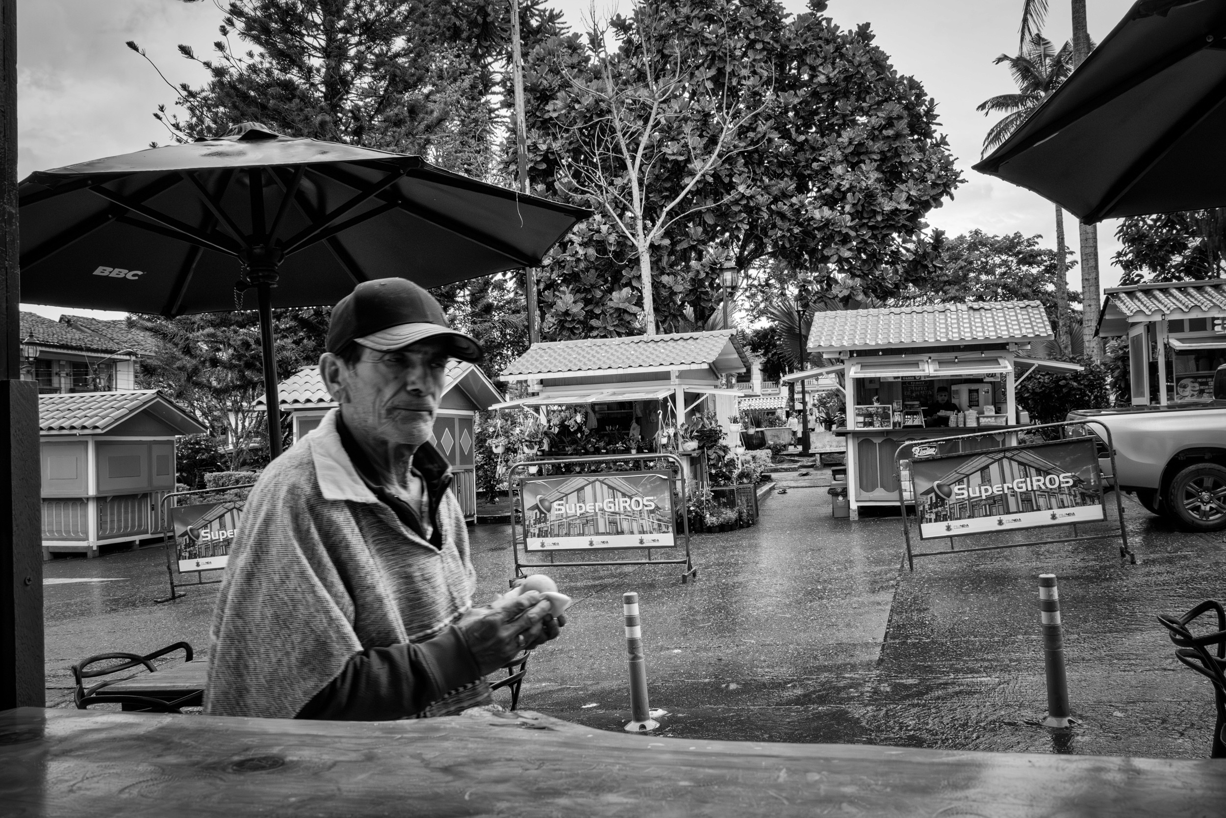 Rainy street scene with people passing by a bar window.