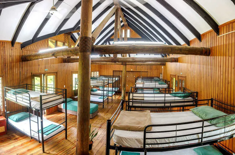 Spacious Fiji dormitory at Uprising Beach Resort with many bunk beds and wooden beams, ideal for groups.