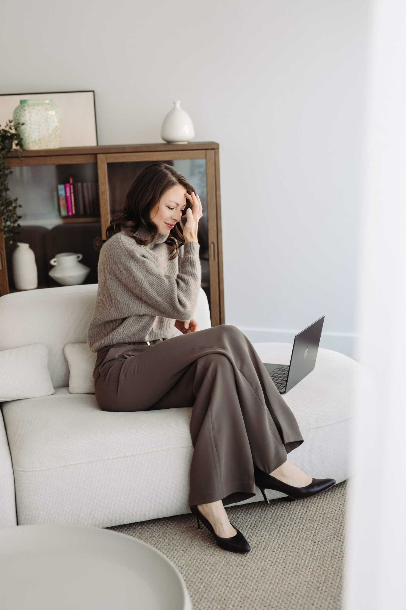 Andréanne Martin assise confortablement sur un sofa avec son ordinateur portable, évoquant son parcours inspirant de la neurologie vers la nutrition.