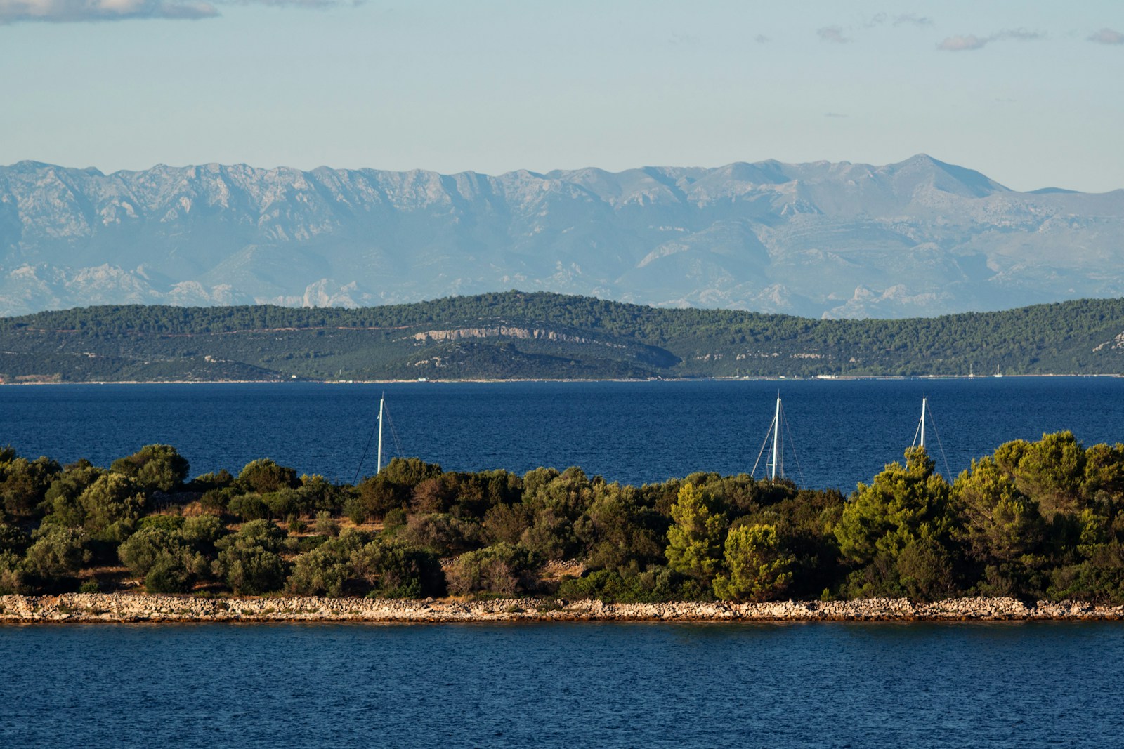 Sailing yachts on calm Adriatic water with mountains in the distance