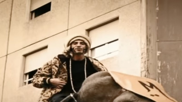 Fotogramma del video di Badabum Cha Cha: Marracash in sella a un elefante davanti a un palazzo della Barona