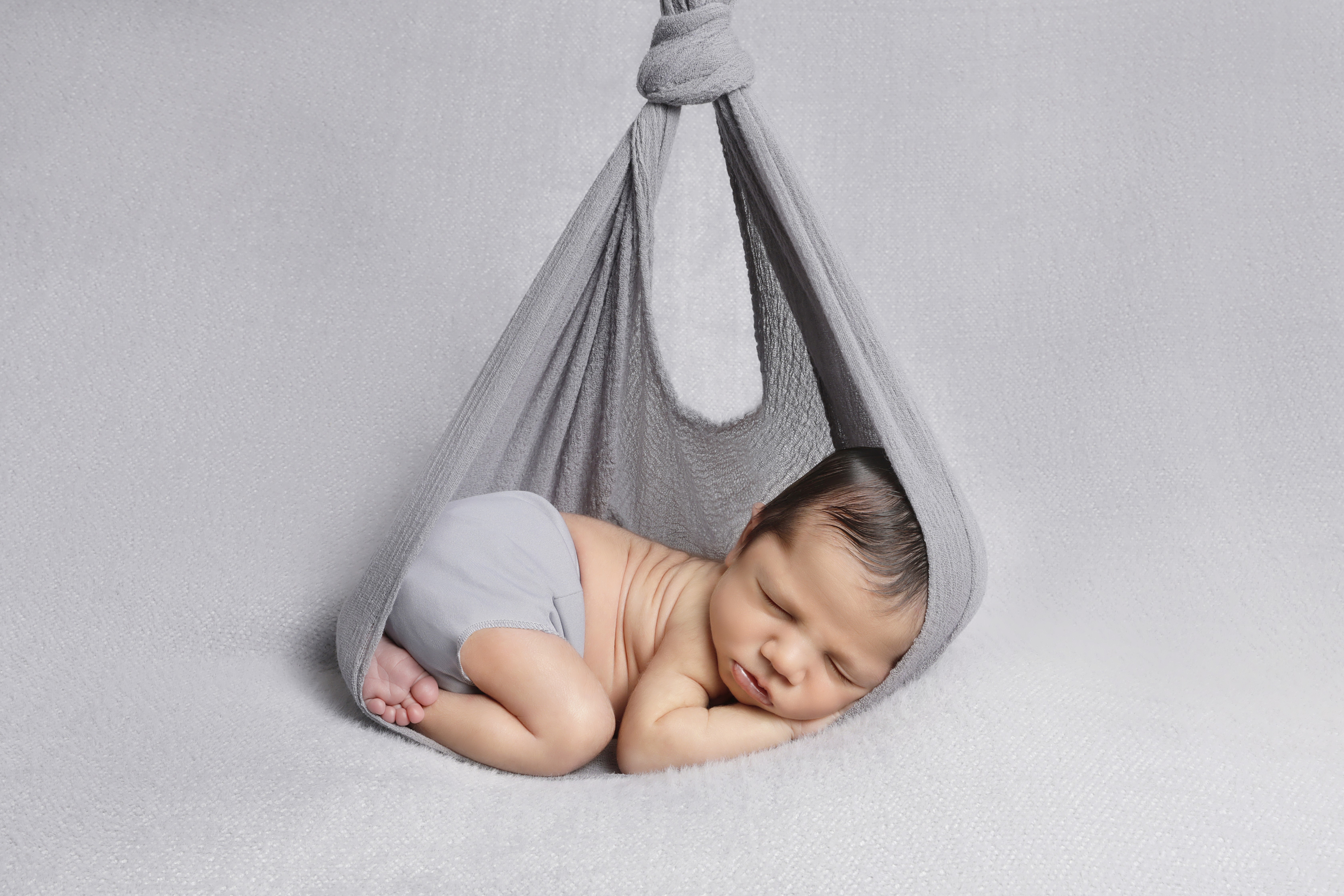 Sleeping newborn tucked inside a fabric wrap.