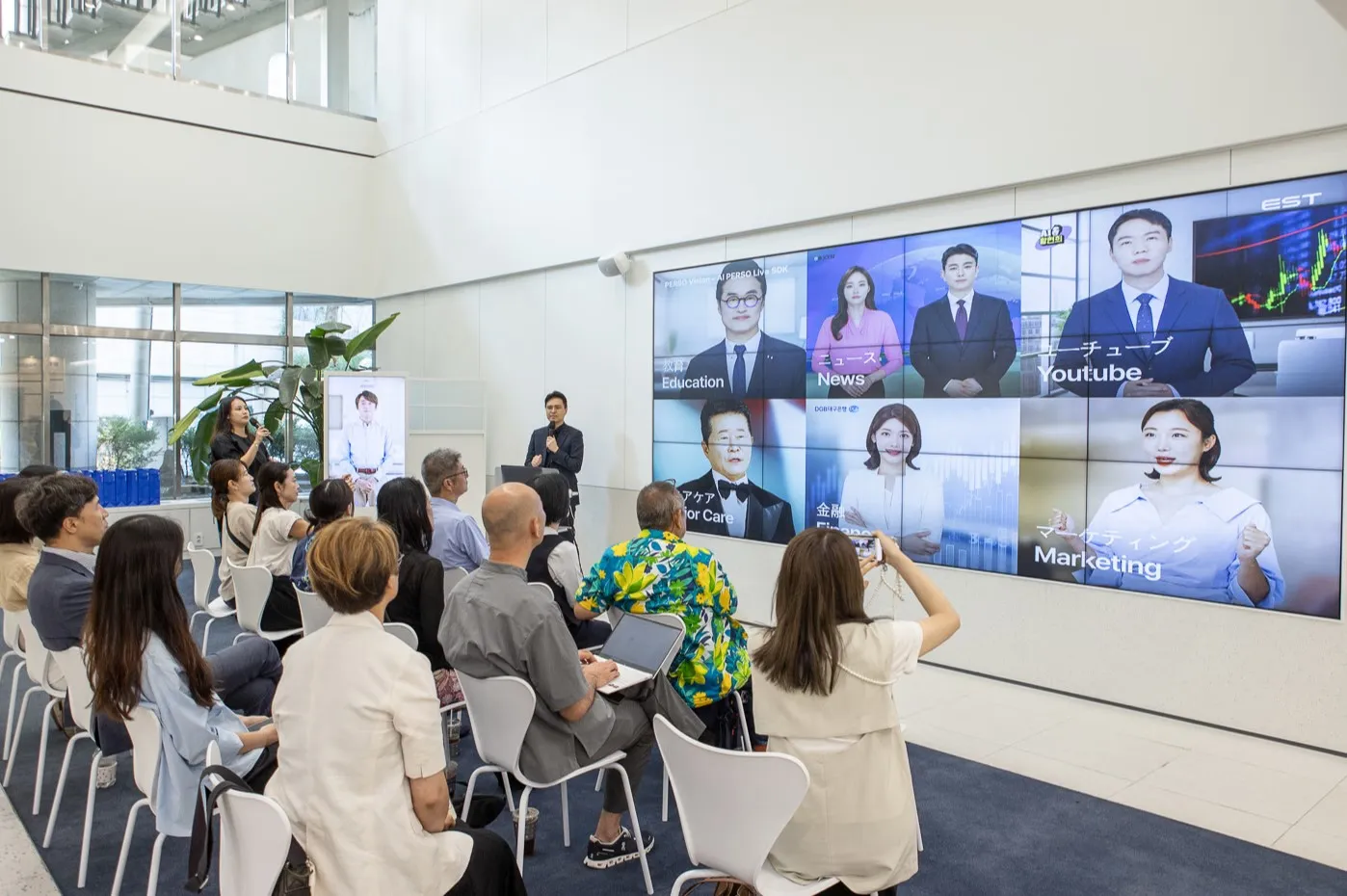 ESTsoft executive presenting the diverse AI Human technology portfolio on a large screen to a delegation of Japanese municipal officials