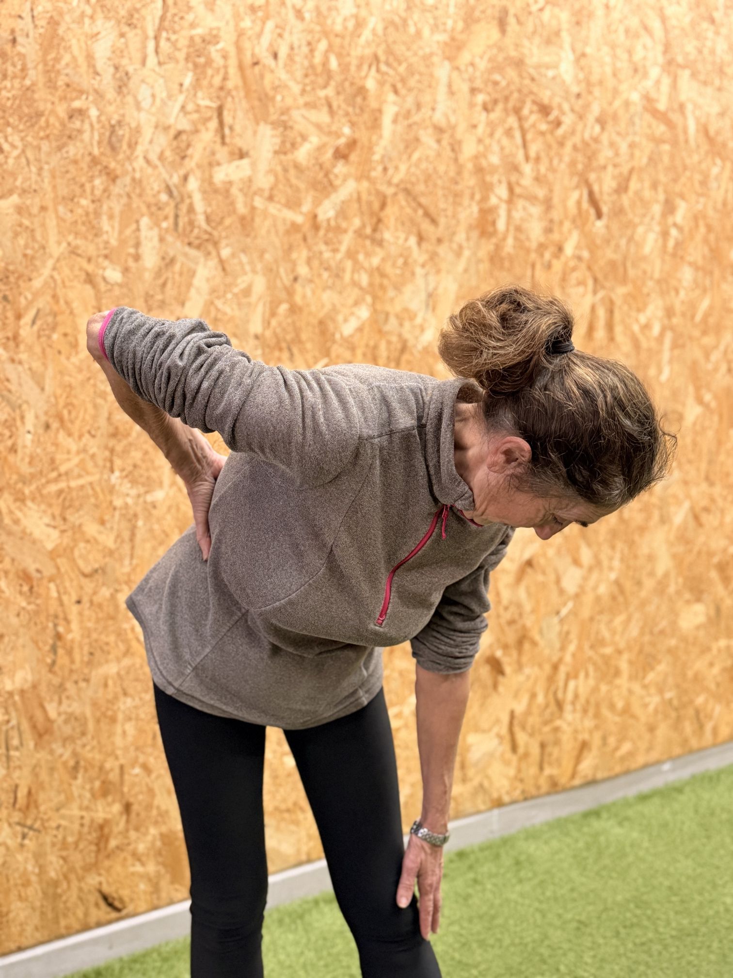 Woman bending over, holding her back in pain.