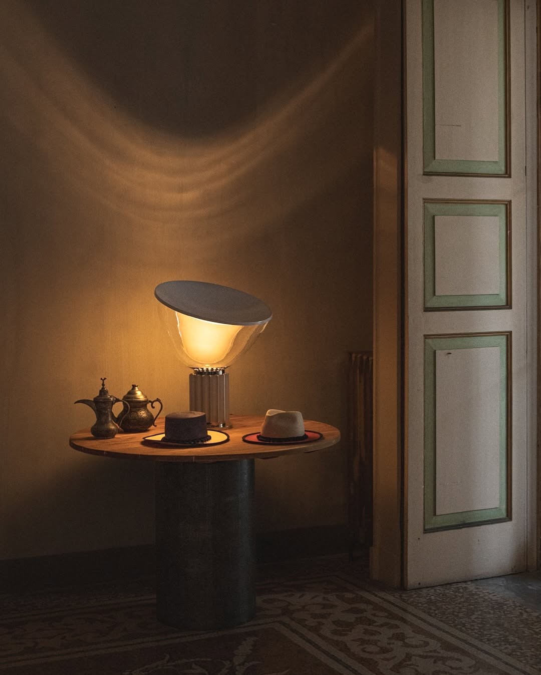 Dark interior with a sculptural flower-shaped lamp, slatted wood wall, and a lounge chair.