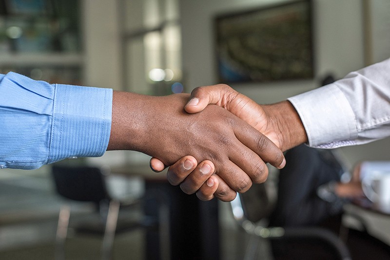 Two people shaking hands in an office.