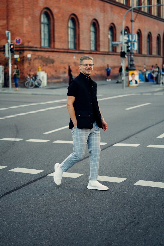 Full-body portrait of a man walking across a street
