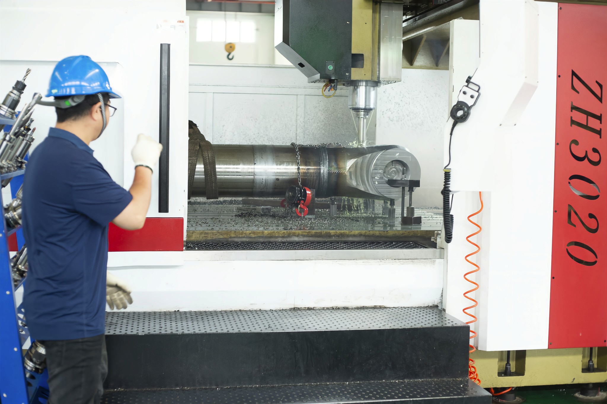 Worker operating CNC machine for large aftermarket mining component.
