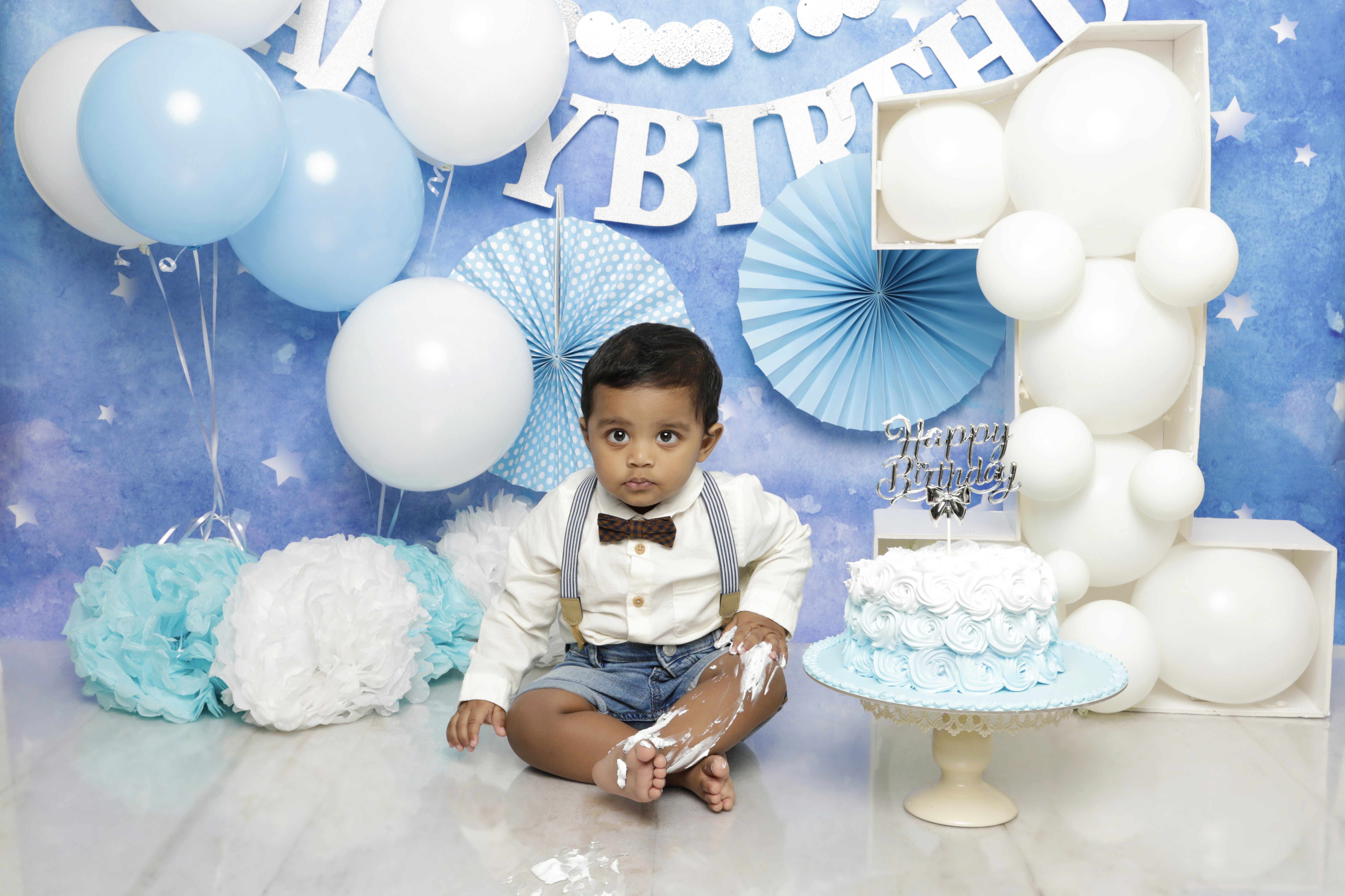 Baby in blue cake smash setup with balloons and cake