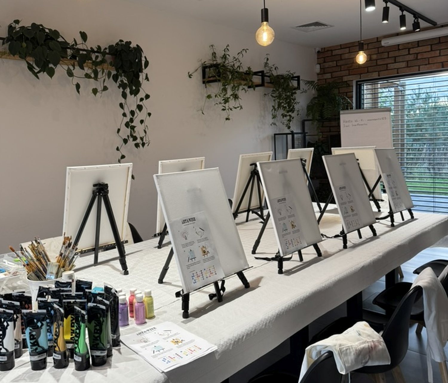 Przygotowana sala na artystyczne warsztaty z winem w restauracji Niedźwiedzia 25 – sztalugi, płótna i farby