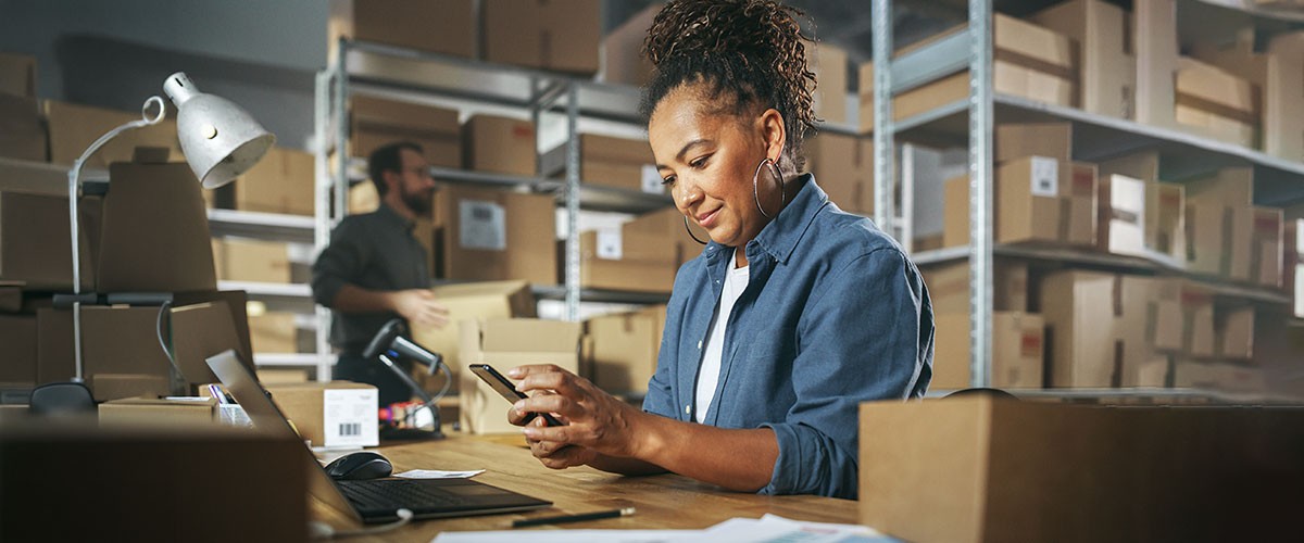 A person sits at a table, reading a book in a library filled with shelves of books.