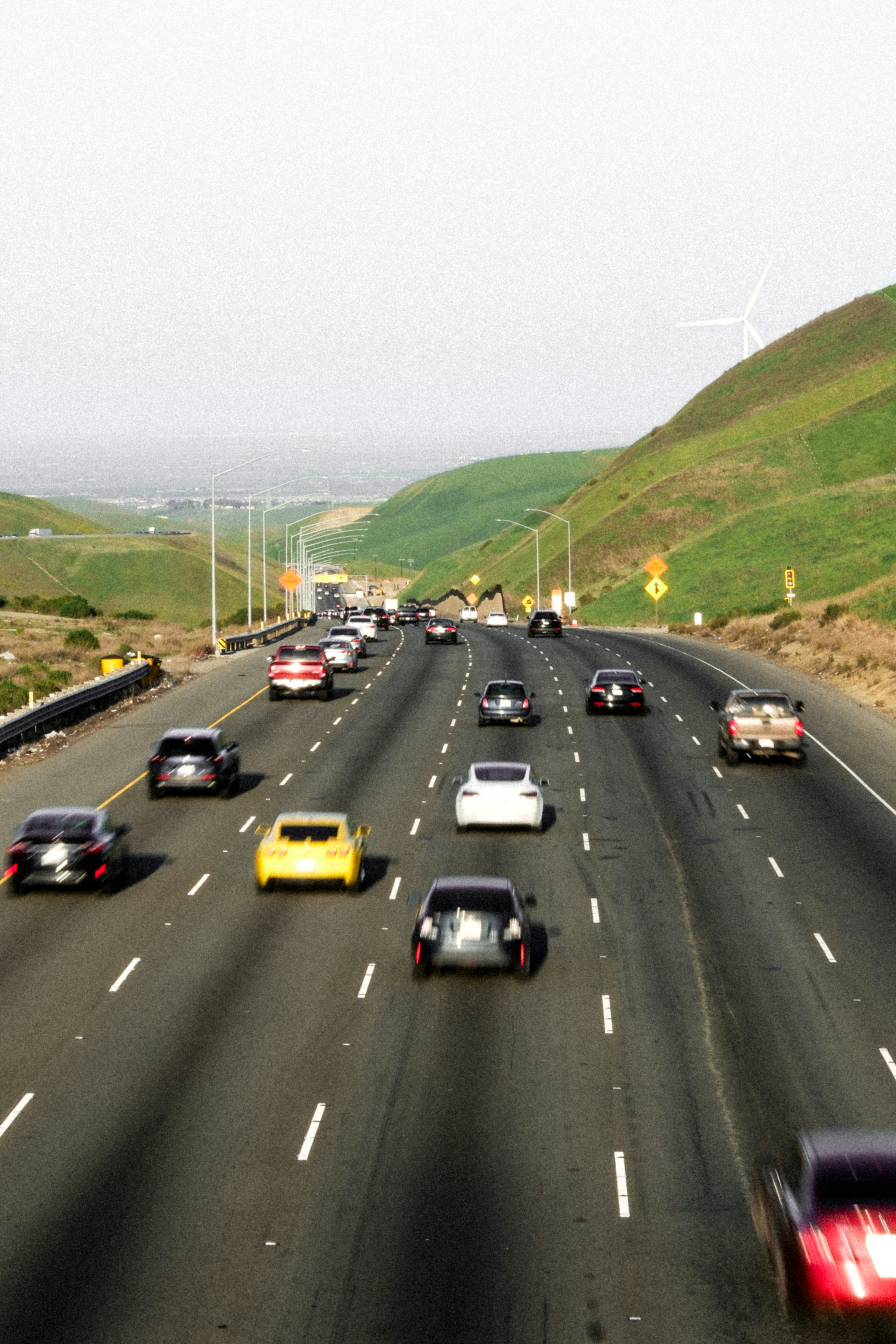 Traffic flows on a highway through a hilly landscape.