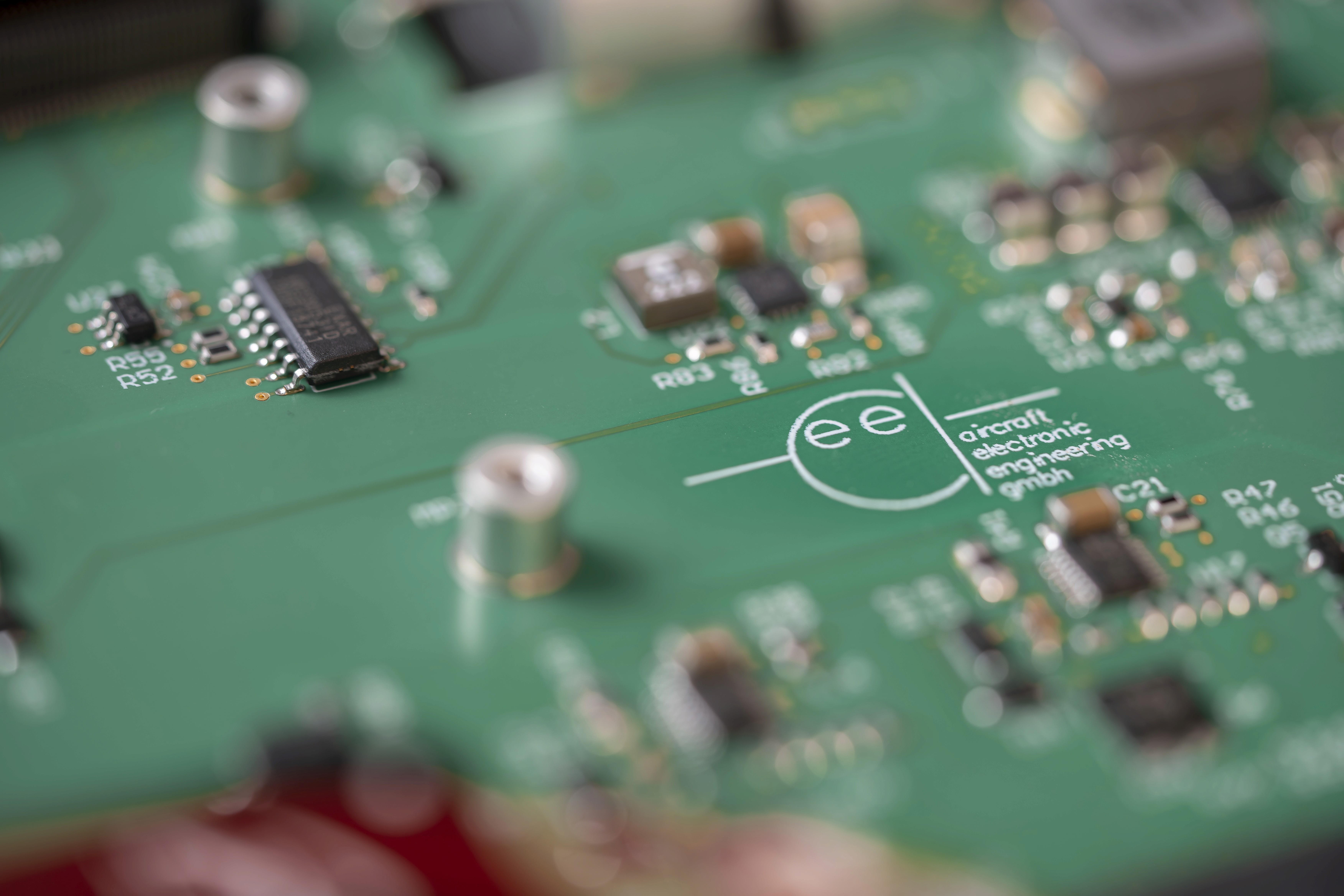 Close-up of a green circuit board with various electronic components and soldered joints.