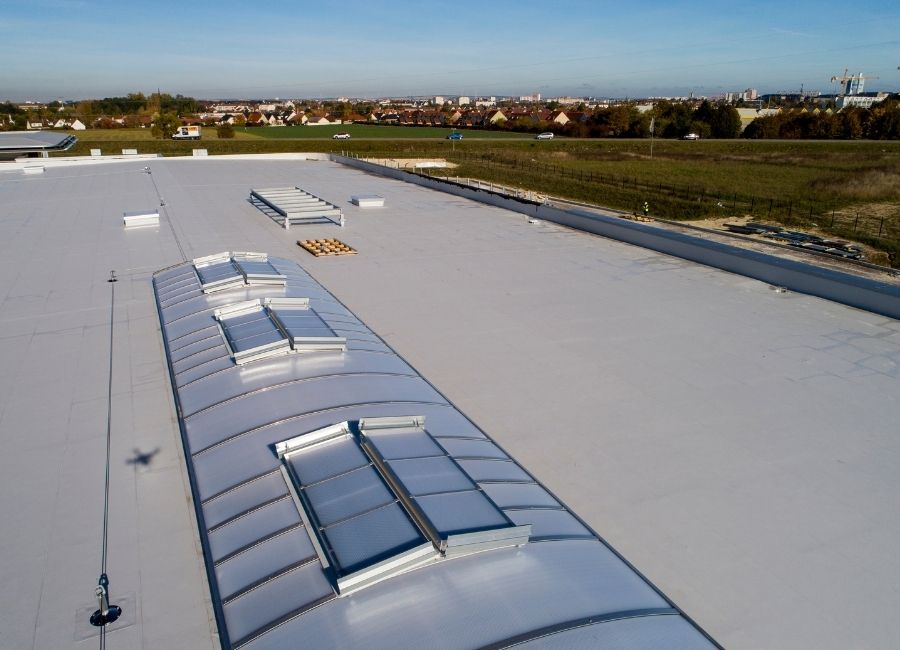 Toiture plate d’un bâtiment avec membrane d’étanchéité en cours de pose.