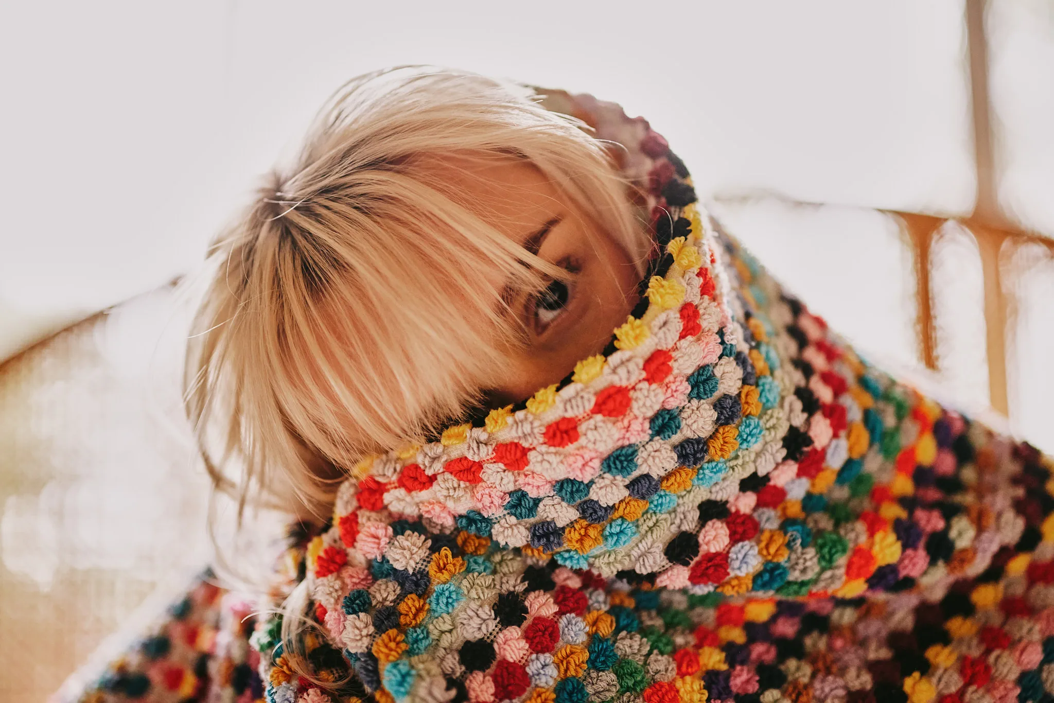 woman peeking over crochet blanket — portrait photography by Tom Kubik