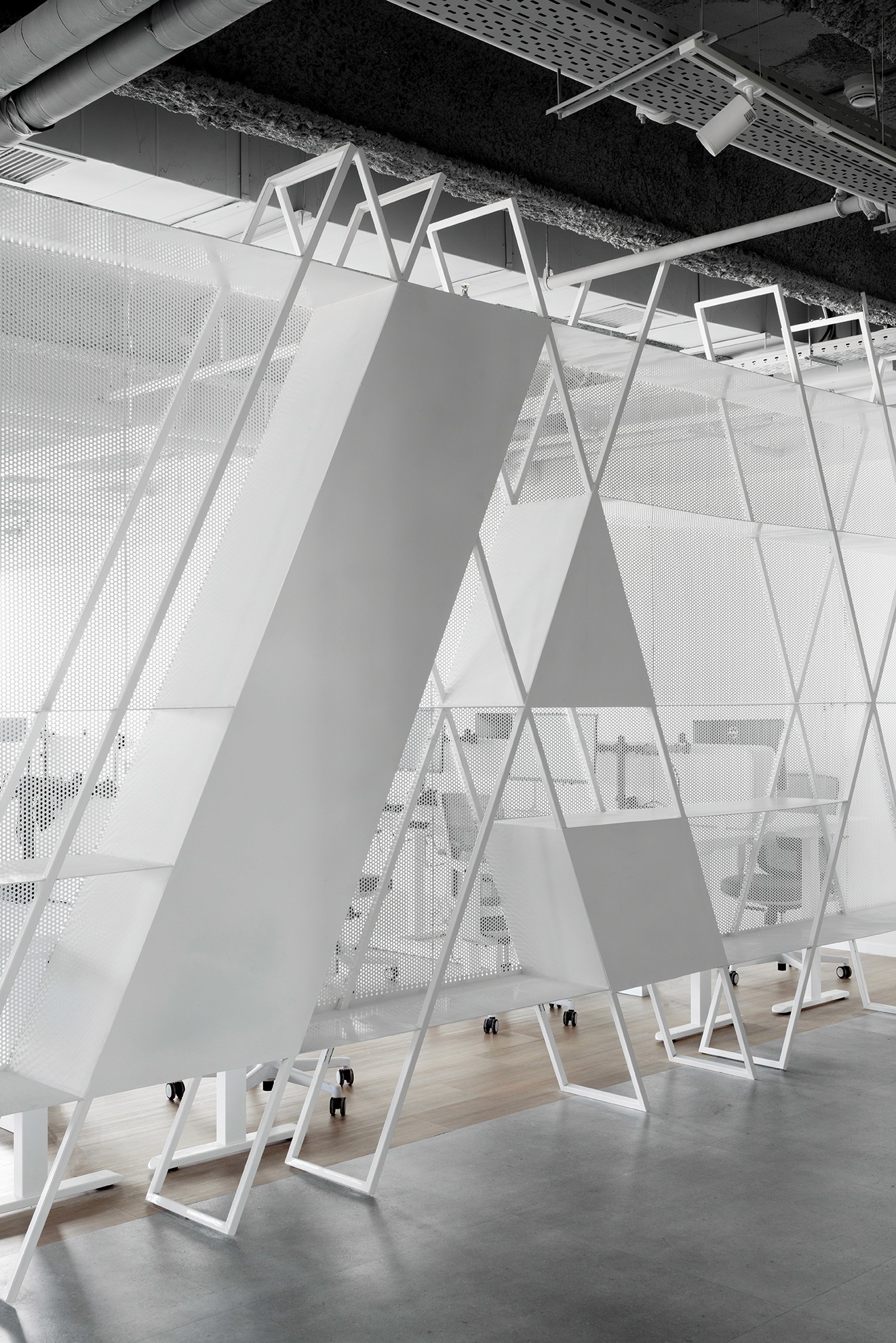 פרט ספרייה: קונסטרוקציית מתכת לבנה בתכנון גאומטרי מורכב – אלמנט פיסולי המשלב מדפים פתוחים ואווריריות