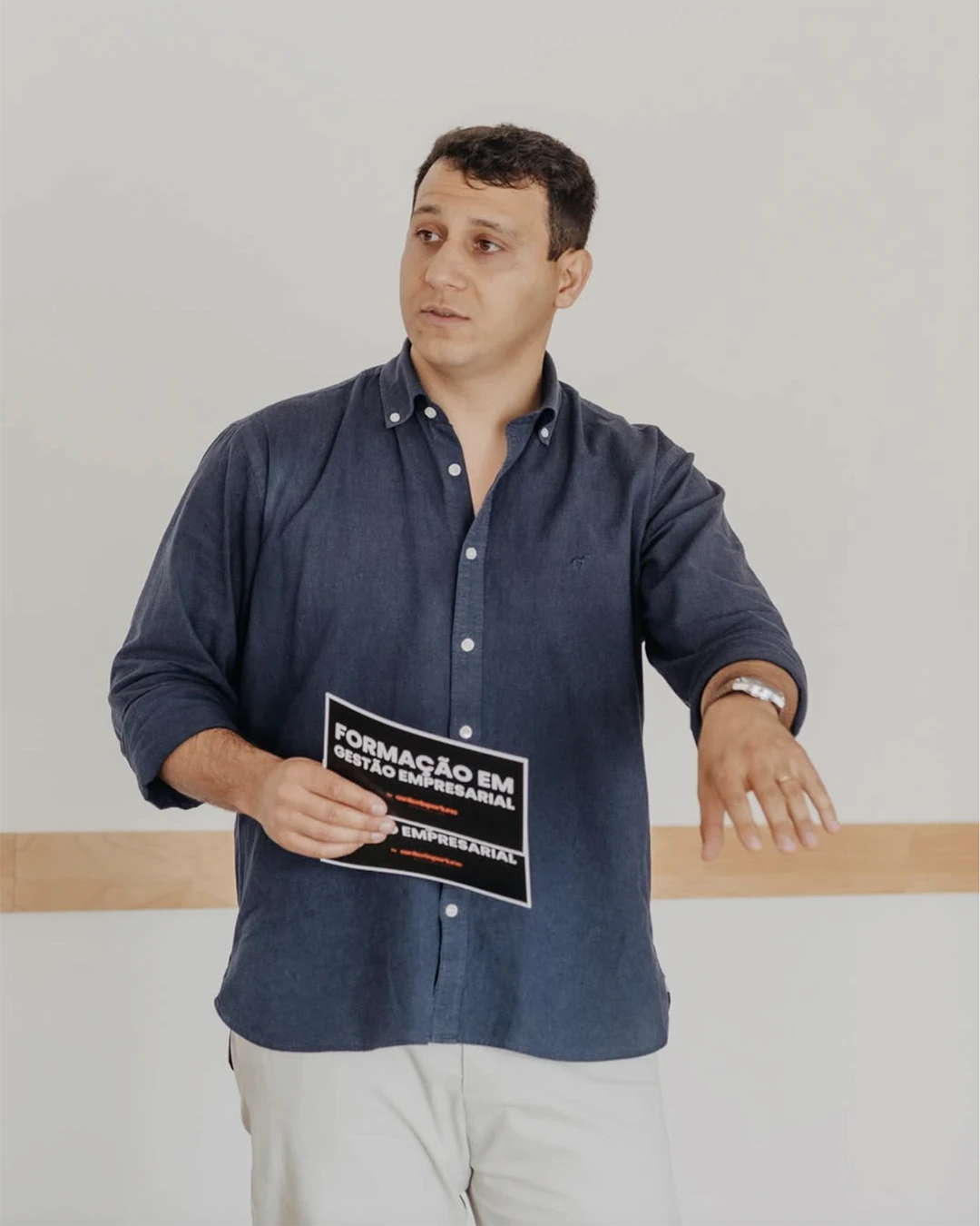 Smiling young man with curly hair, wearing a dark hoodie, against a softly lit background.