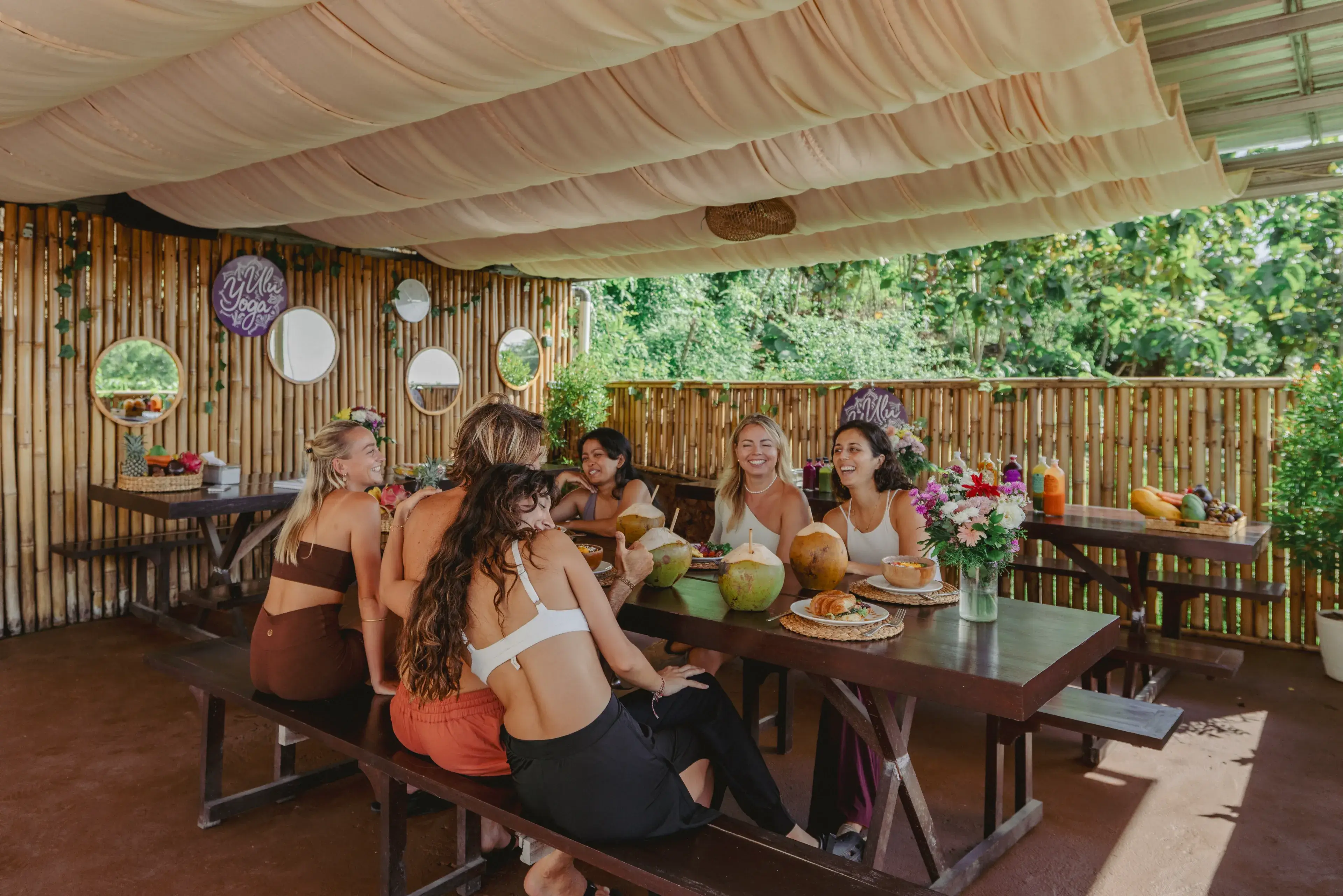 Yoga students enjoying healthy meals and community connection at the bamboo cafe during their 200hr Bali yoga retreat