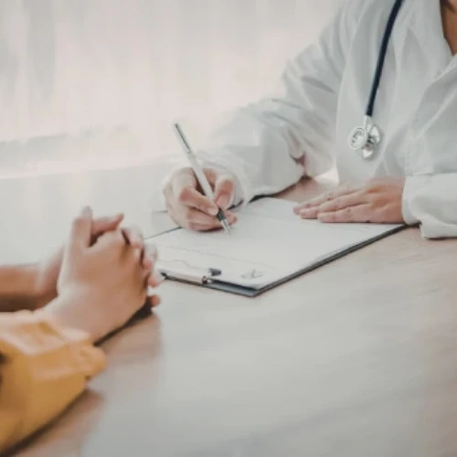 Doctor writing notes on a clipboard during a confidential patient consultation at a medical practice in Coburg, serving Melbourne's northern suburbs.