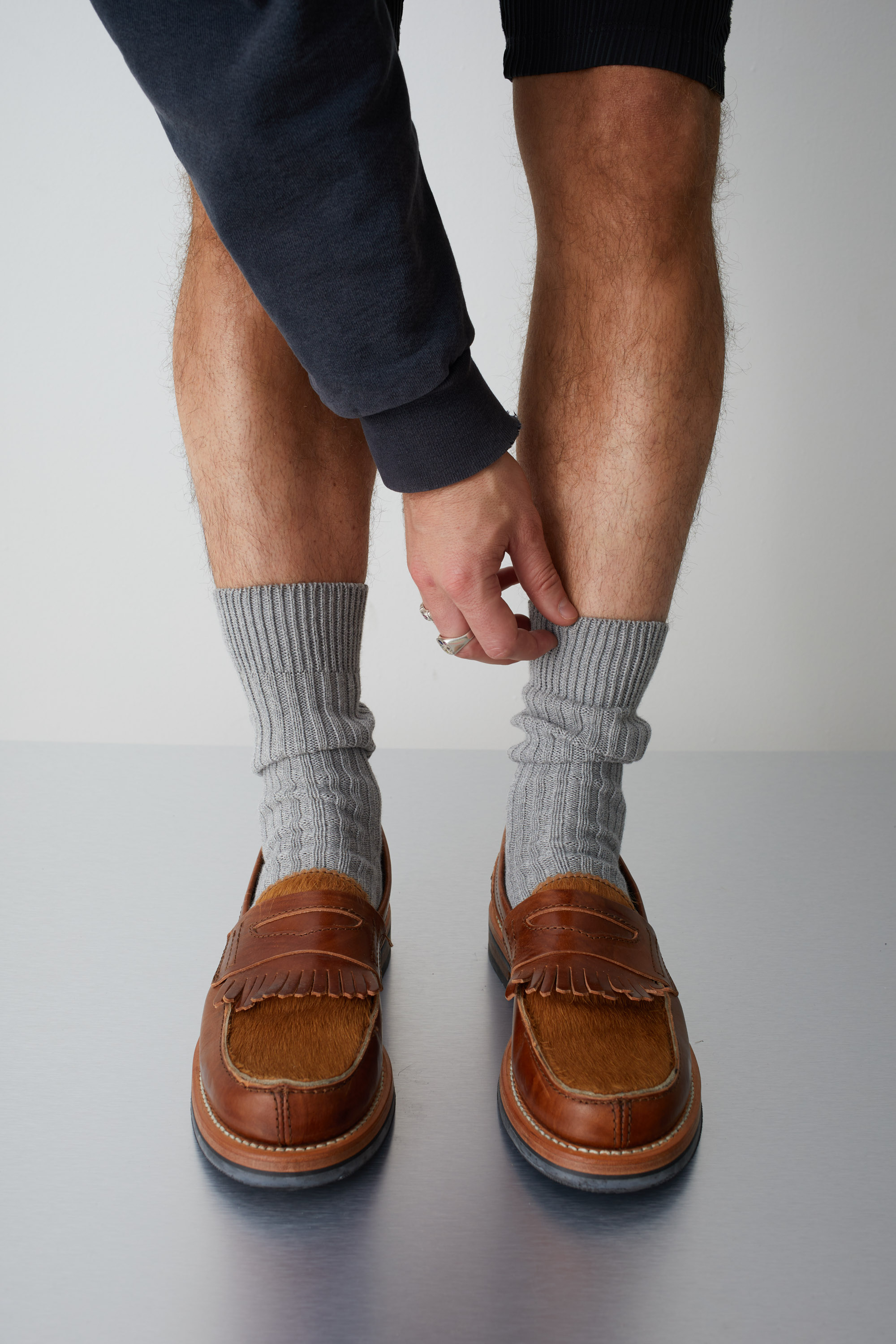 Les pieds d'une personne portant des mocassins marrons et des chaussettes grises