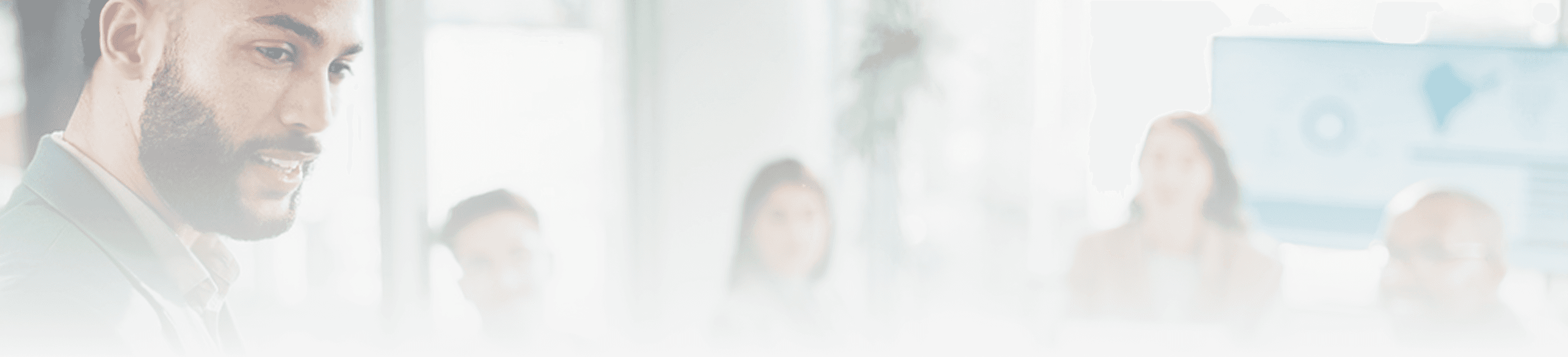 A blurred, high-key image of a business professional speaking in front of an audience in a conference setting.