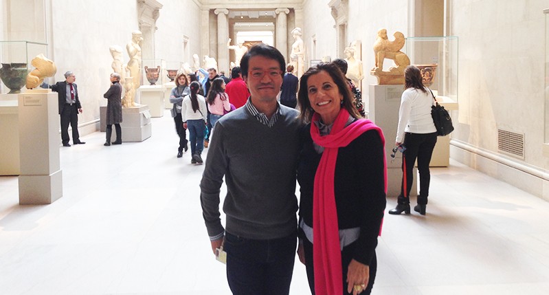 A photo of a man and a woman standing in an art gallery hallway among other people..