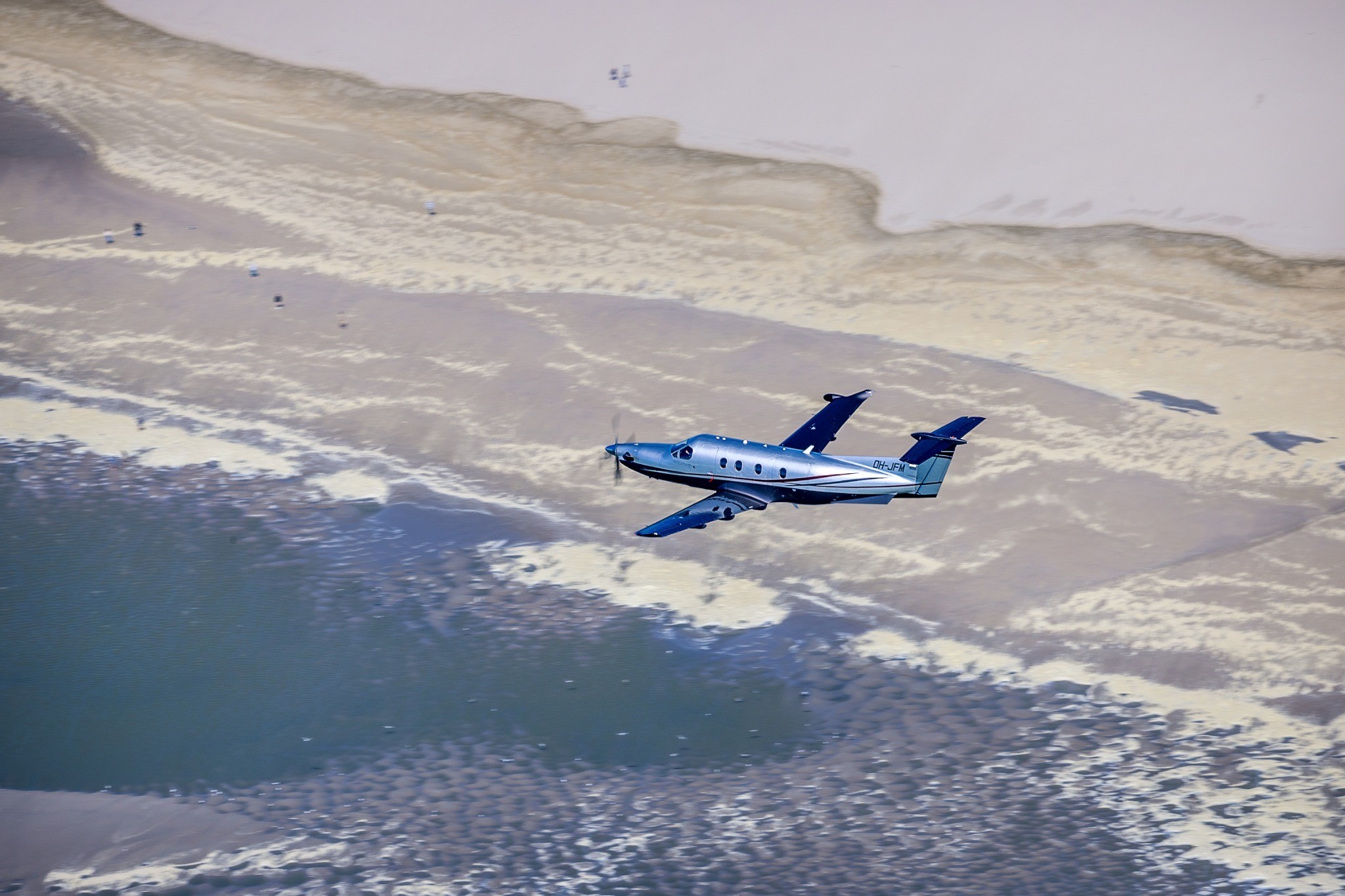 Pilatus PC-12 flying over beach
