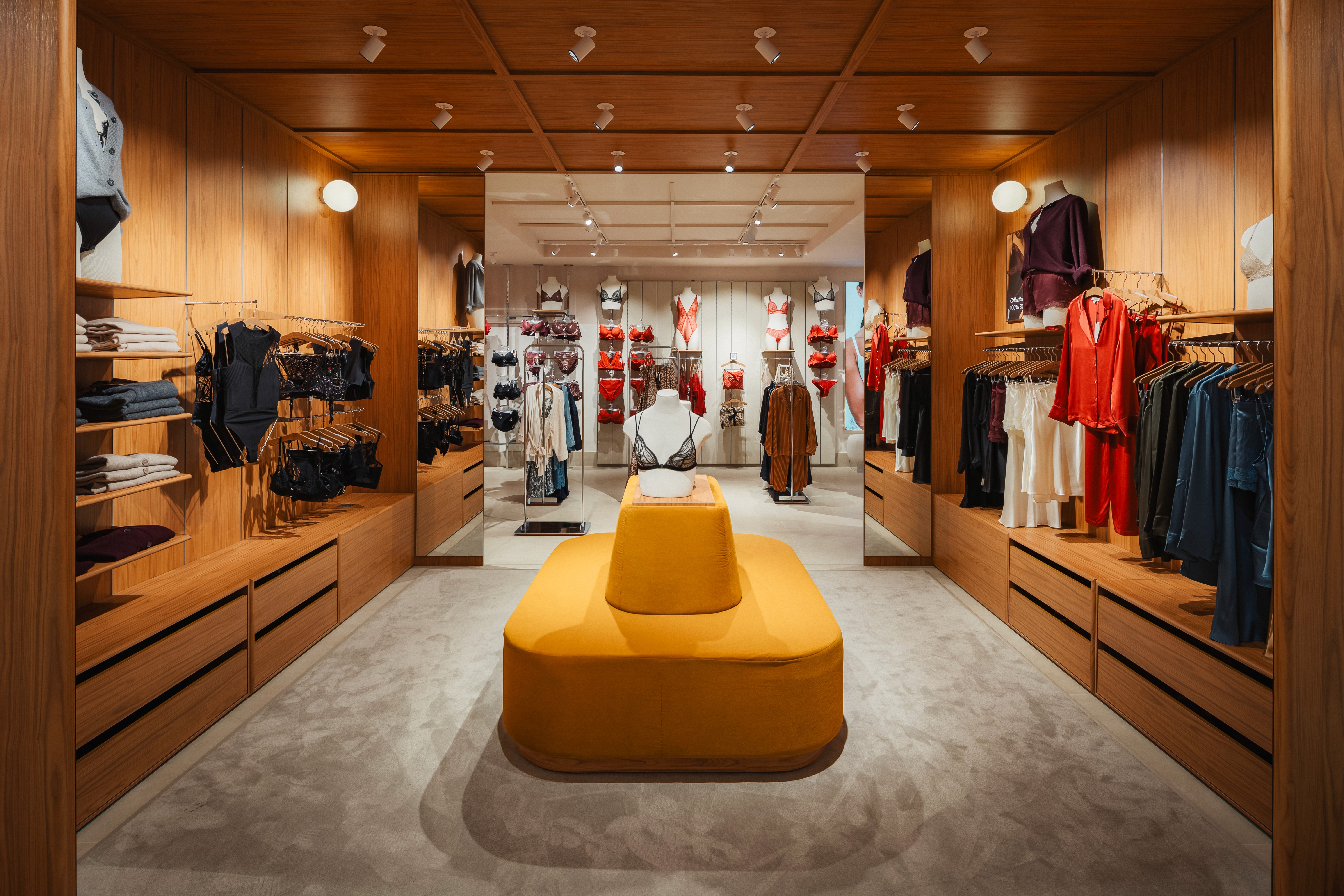 Allée centrale avec canapé jaune moutarde, lingerie noire et rouge aux murs, plafond et sols en bois