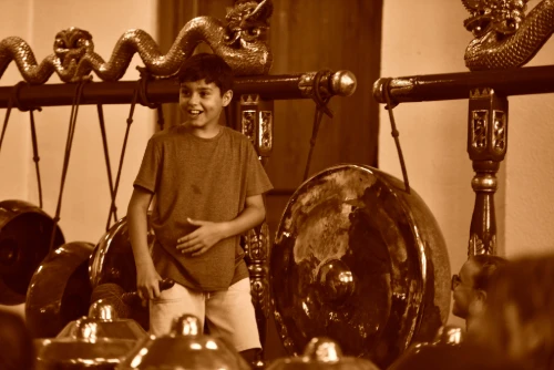 Un garçon souriant devant un gong javanais.