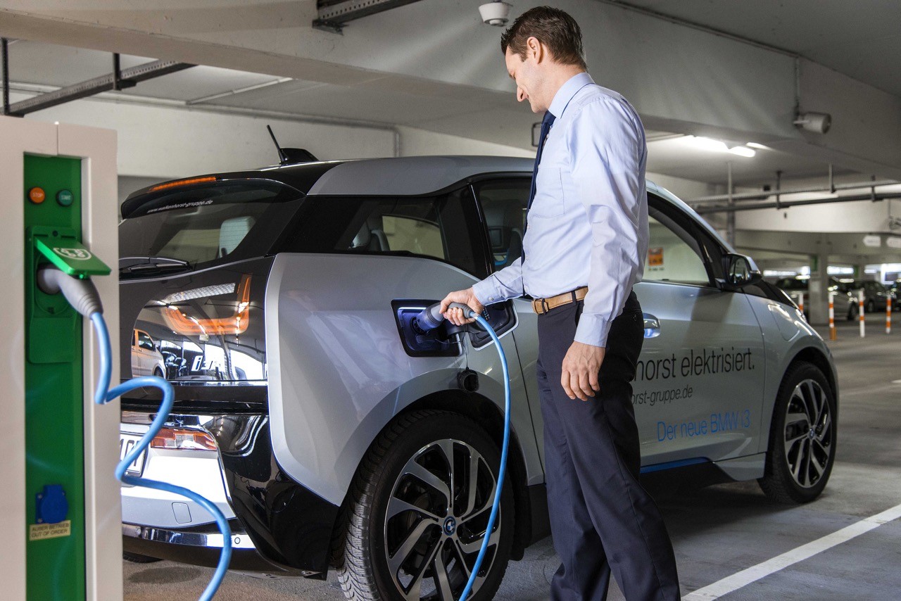 Mann lädt Elektroauto an Ladestation. Nachhaltige Mobilität und E-Auto-Technologie.
