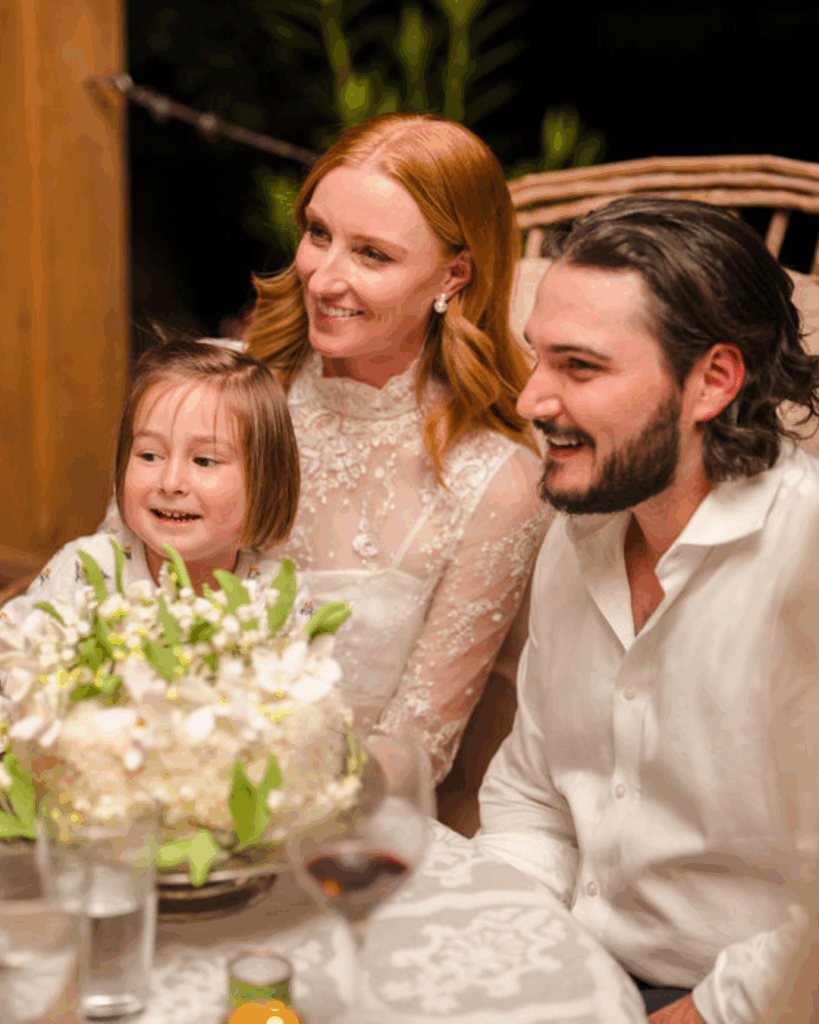 Newlyweds seated at dinner with a young girl