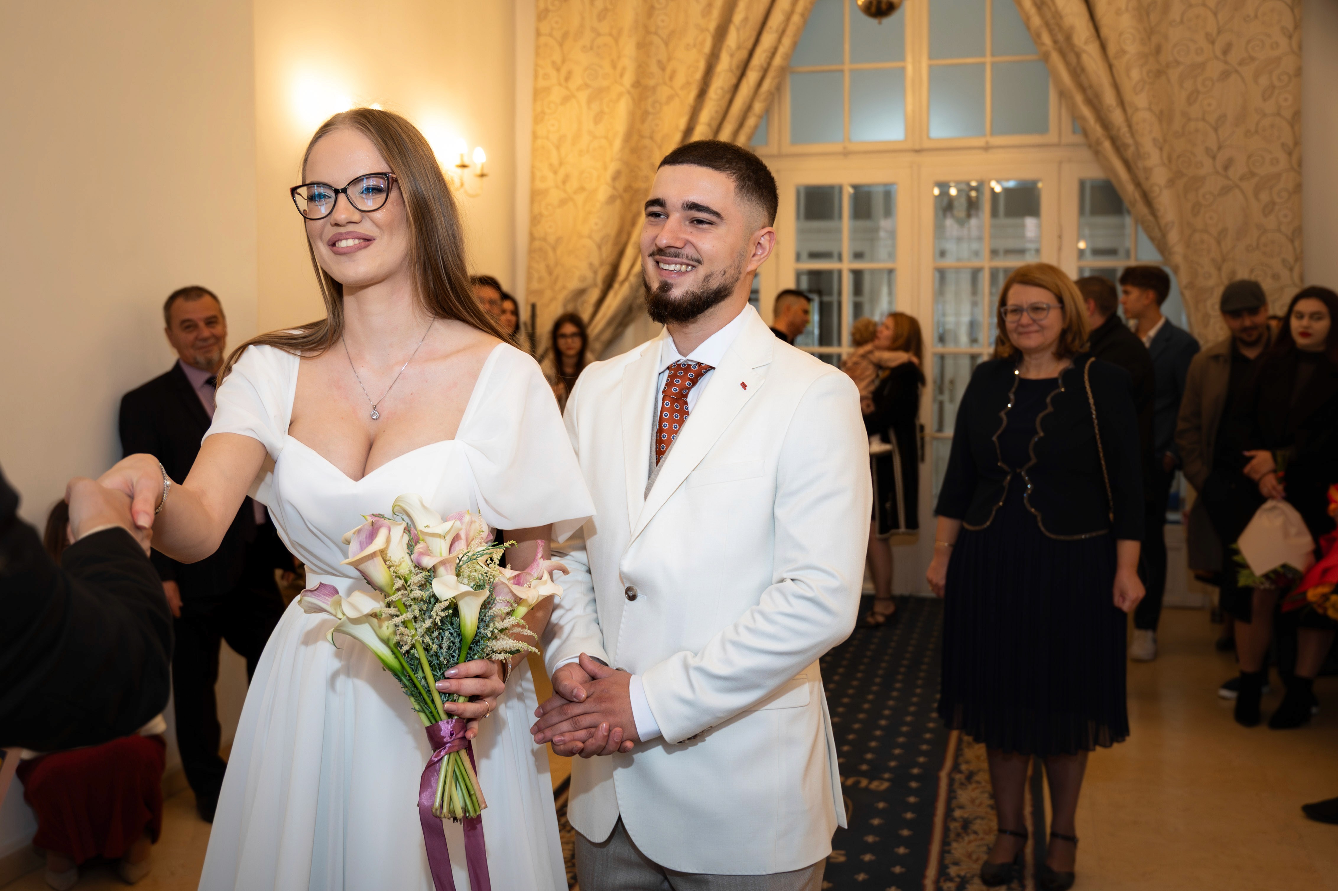 Soț și soție în sala de cununie civilă, zâmbind emoționați.