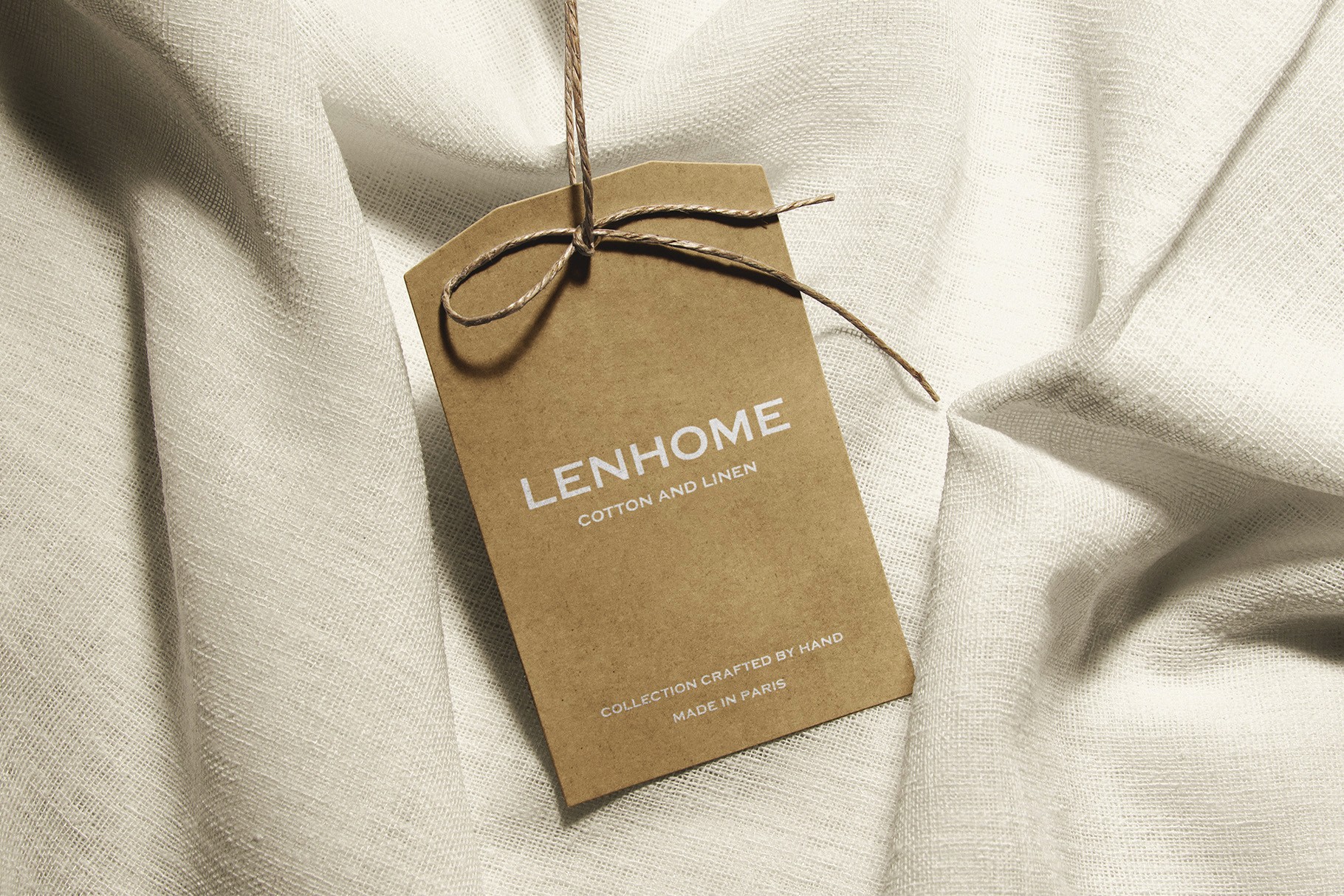 Kraft paper tag mockup with the LENHOME logo, placed on soft fabric, emphasizing an eco-friendly and handmade aesthetic.