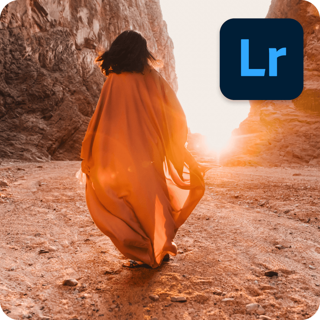 A person wearing orange looking toward the sun through two rocky hills