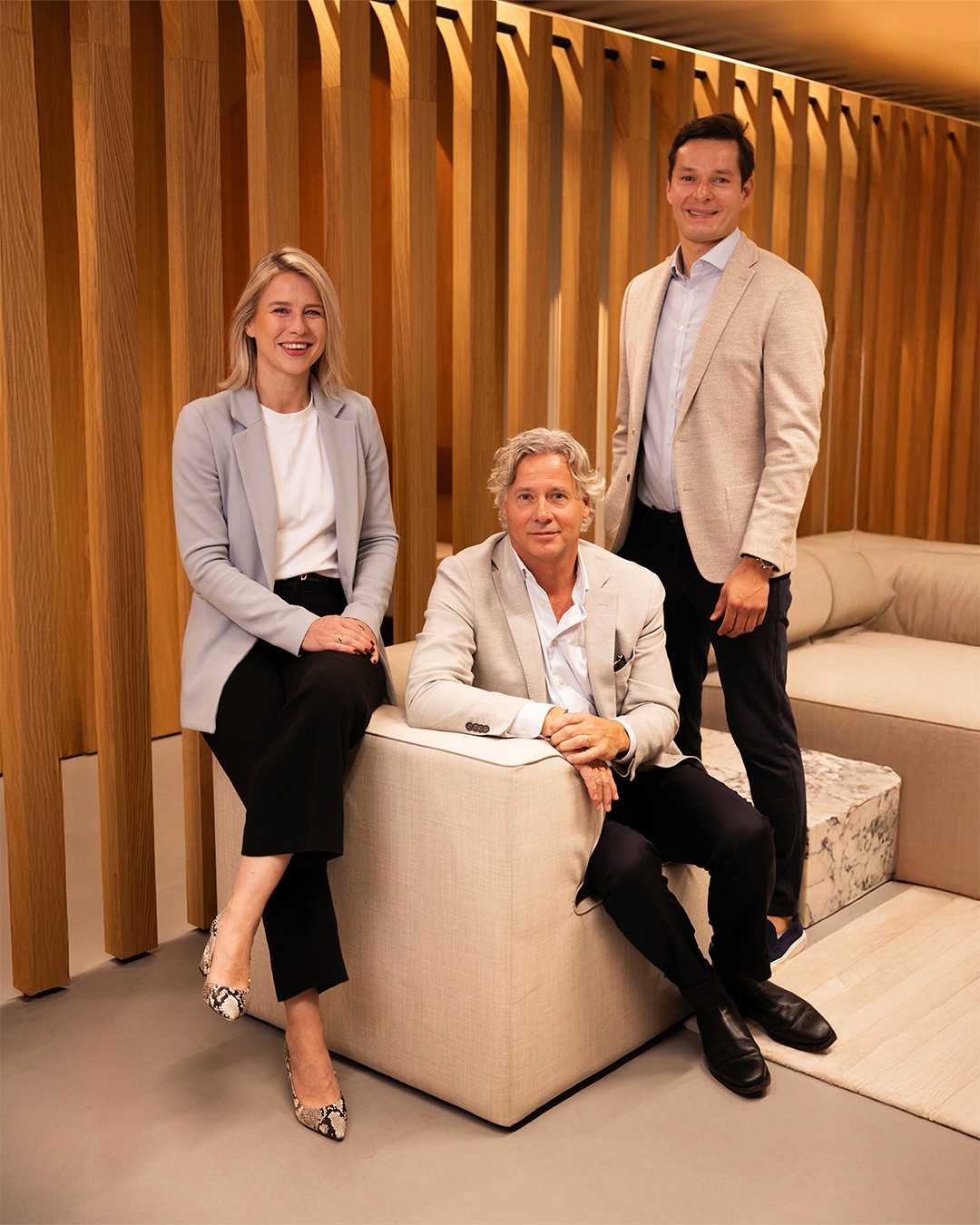 A modern restaurant with a teal coffered ceiling, white curtains, large windows, dark leather chairs, wooden tables, and a white dome lamp on a marble counter.
