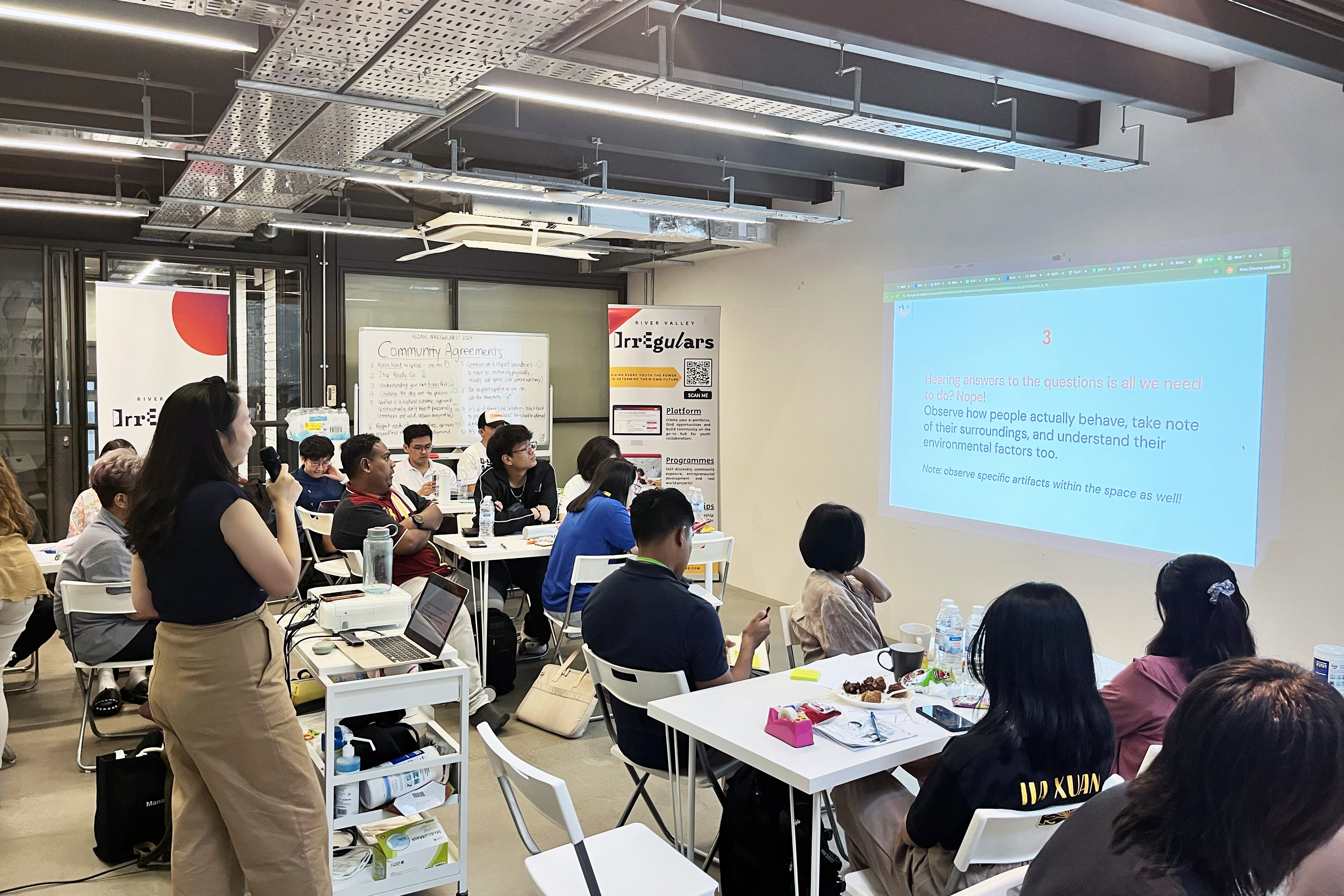 A group of workshop participants attentively listening to a presentation on Empathy in Design Thinking