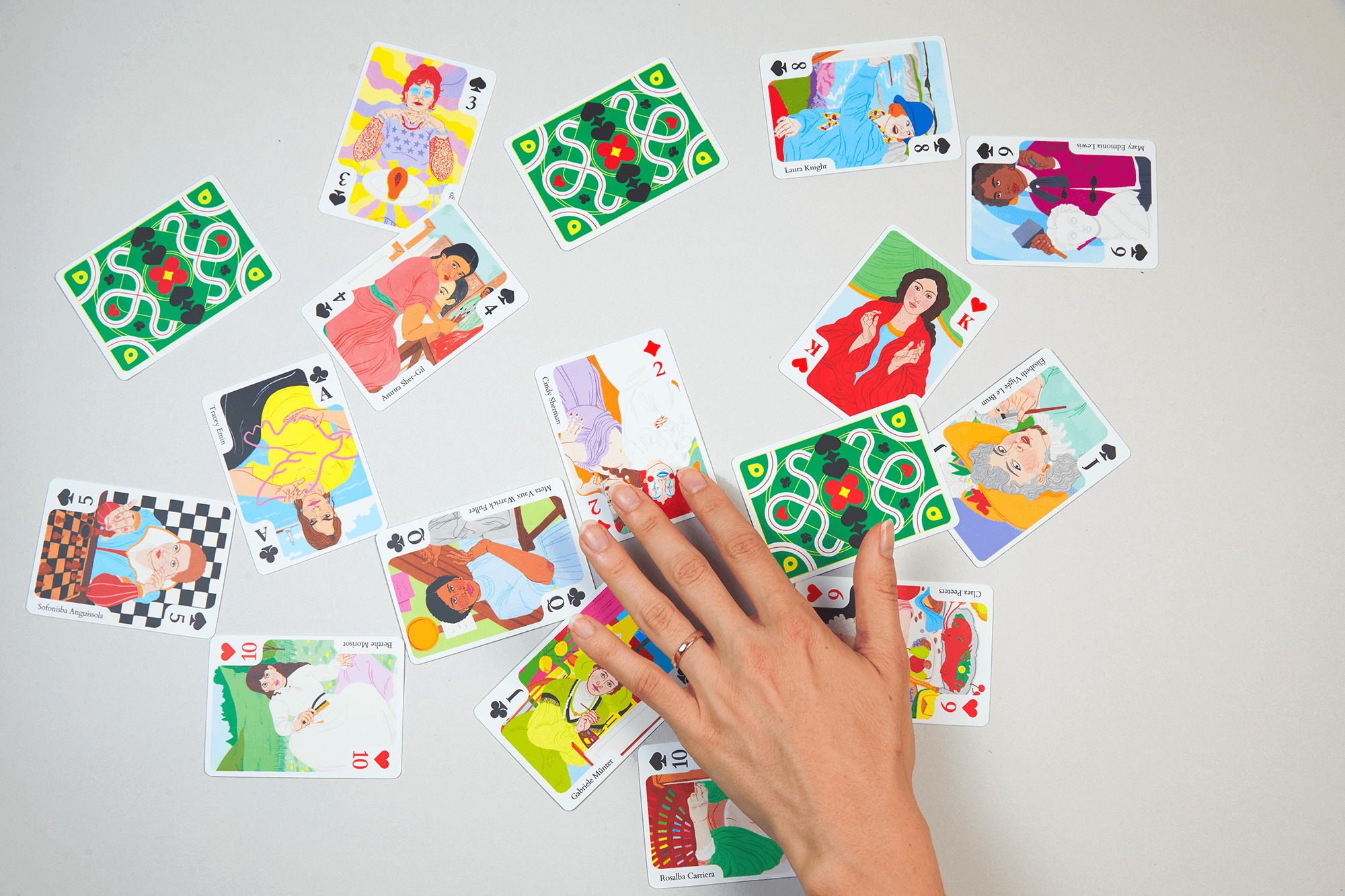 Hands arranging illustrated playing cards from the Thames & Hudson Gift Lab collection.