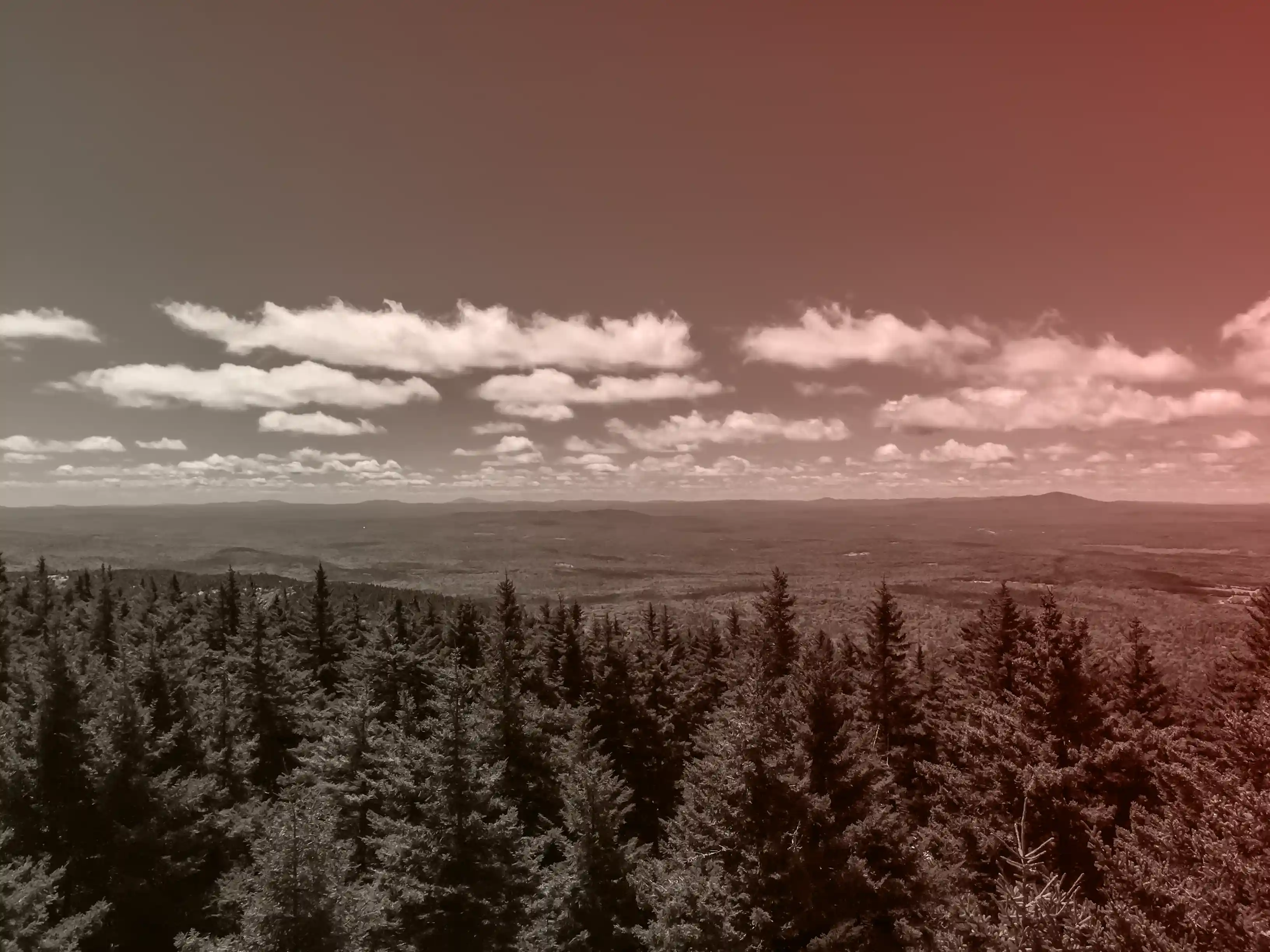 New Hampshire treeline and hills viewed from above, with a red gradient overlay