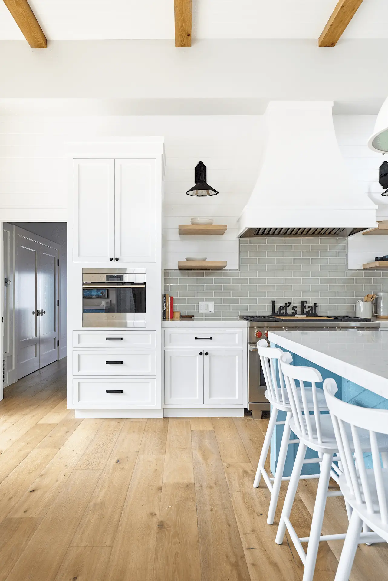 Modern farmhouse kitchen with white cabinetry and bar stools in North Tustin Remodel & Addition. Photo by Todd Huge.