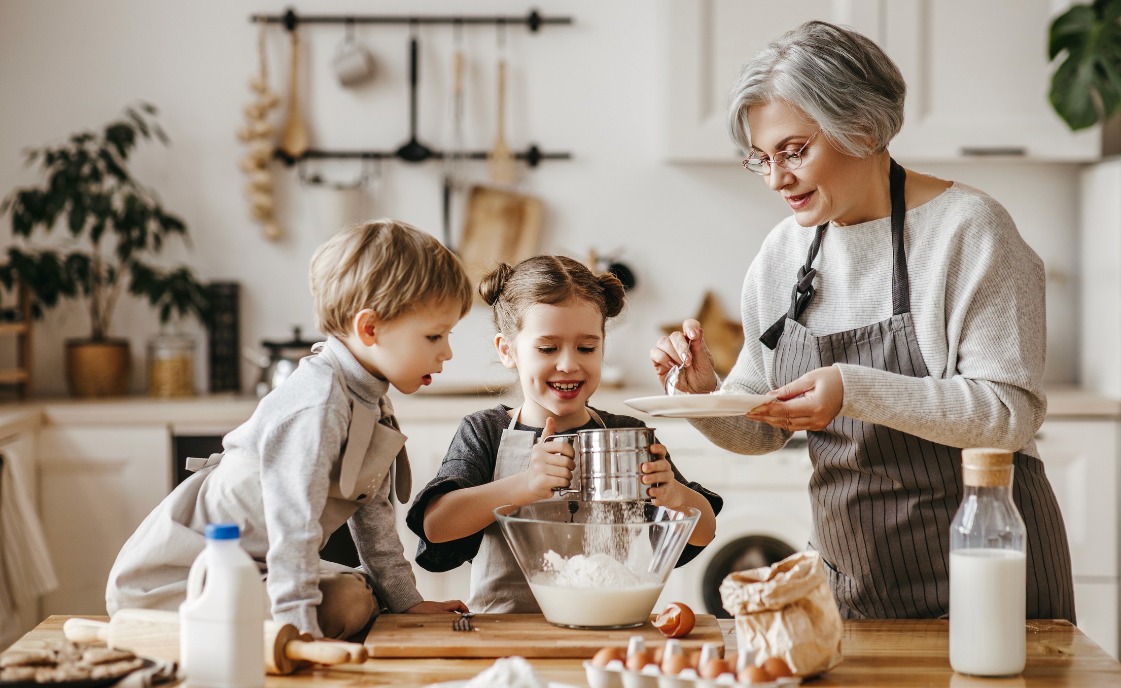 Carmen cocinando en la cocina con sus dos nietos pequeños, compartiendo una actividad familiar