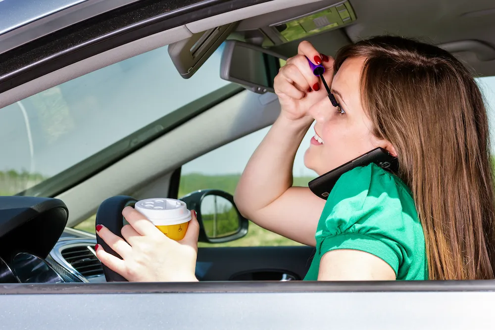 Woman with coffee, makeup, phone in car