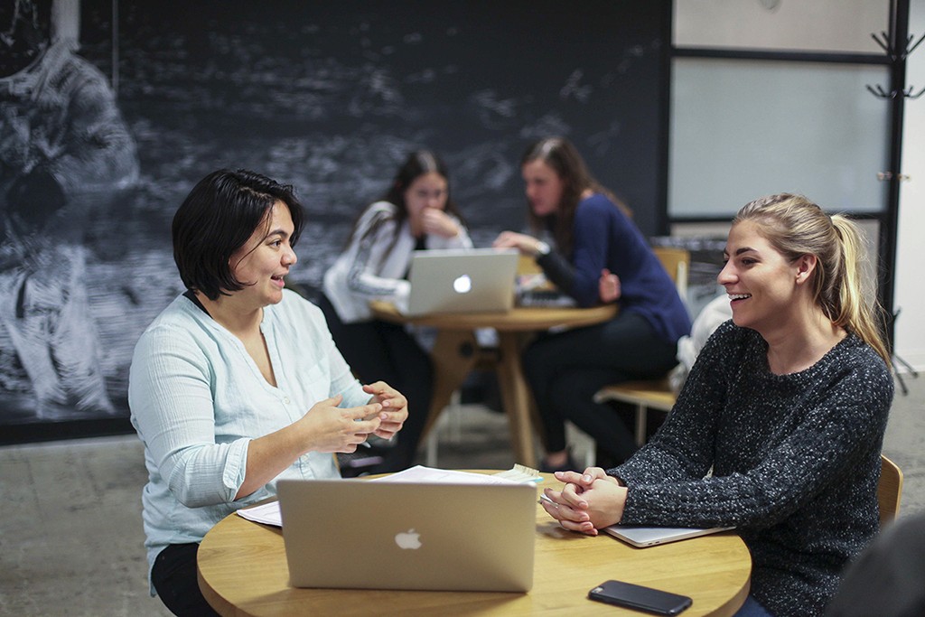Two practitioners in close conversation at a table, one gesturing openly mid-exchange.