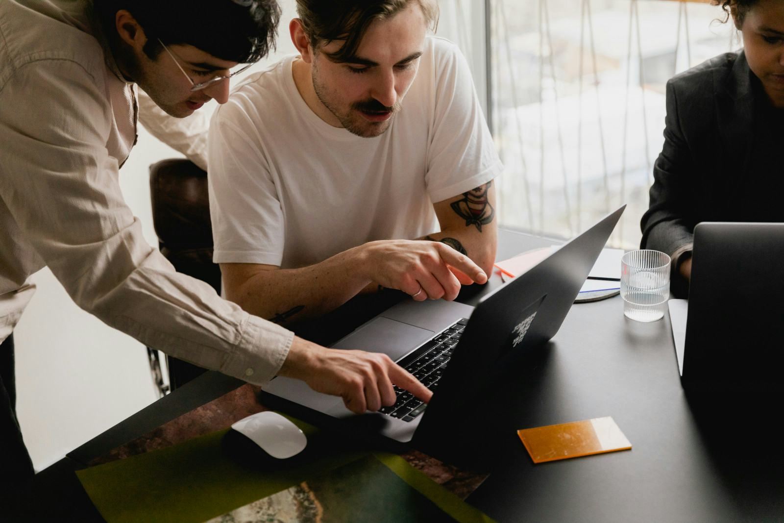 multiple people staring into a laptop