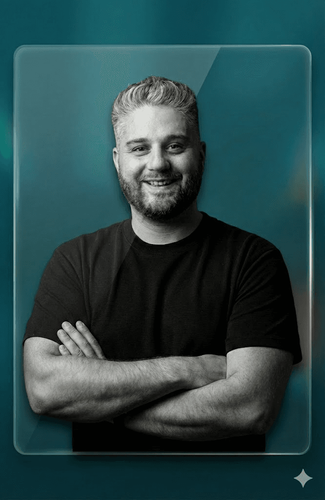 A smiling woman with her arms crossed, standing against a dark green background. She has long, dark hair.